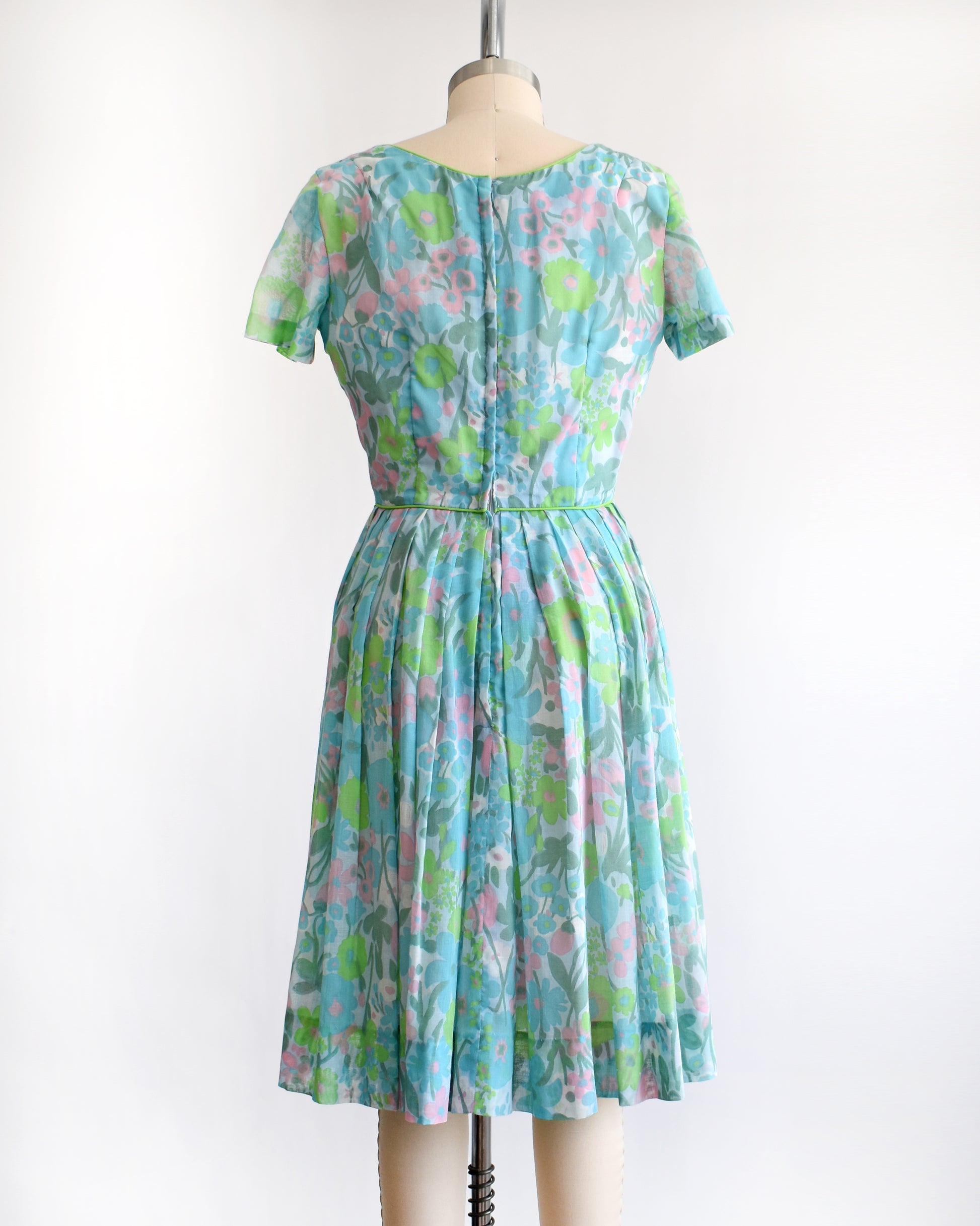 back view of a vintage 1960s floral dress on a mannequin against a white background