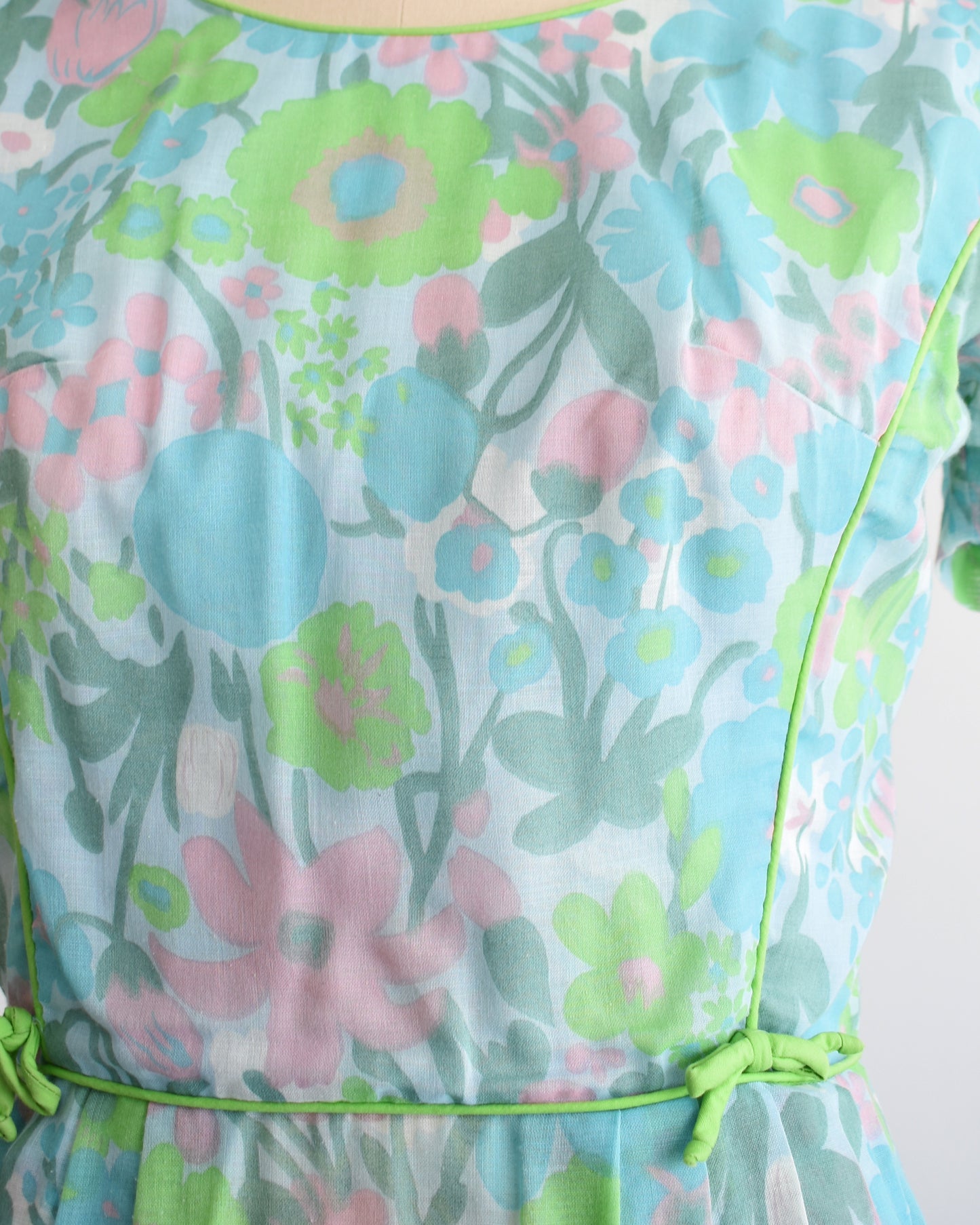 close up of a vintage 1960s floral dress on a mannequin against a white background