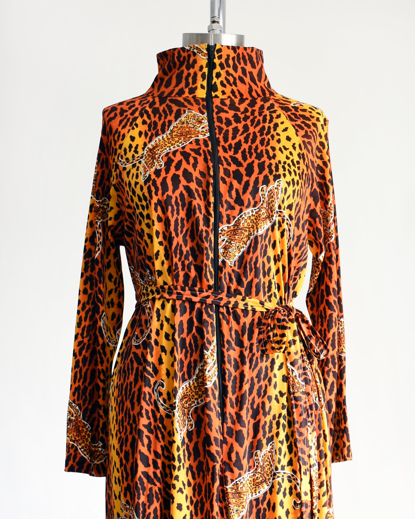 close up of a vintage 1970s leopard print long sleeve lounge dress with matching tie belt that has the zipper zipped all the way up