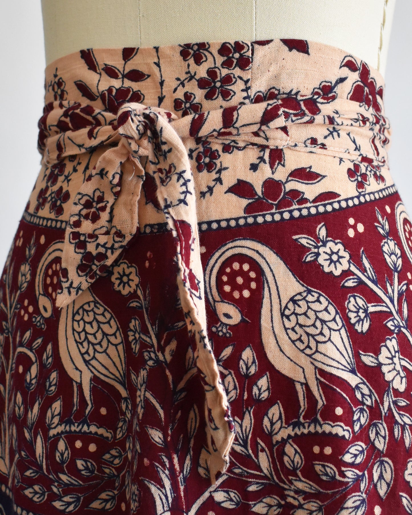 close up of the tied waist on a vintage 1970s block print skirt on a mannequin against a white background