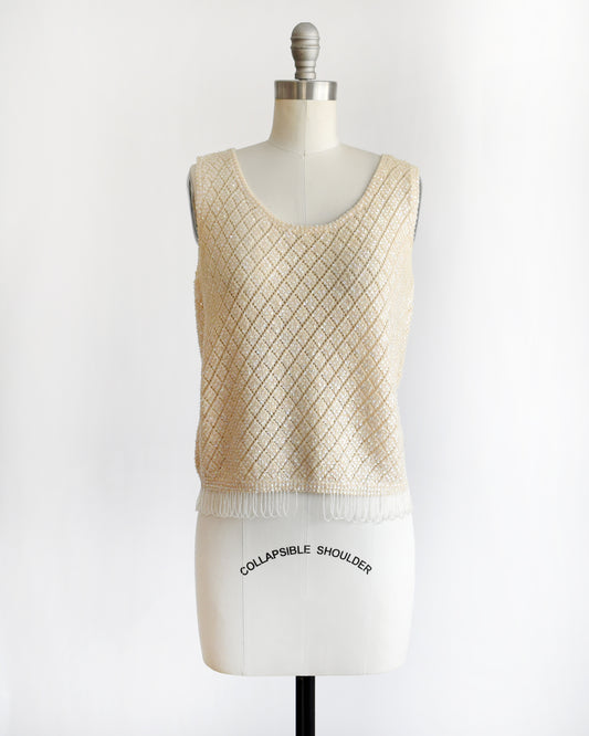 A vintage 1960s cream sequin and beaded top on a mannequin against a white background
