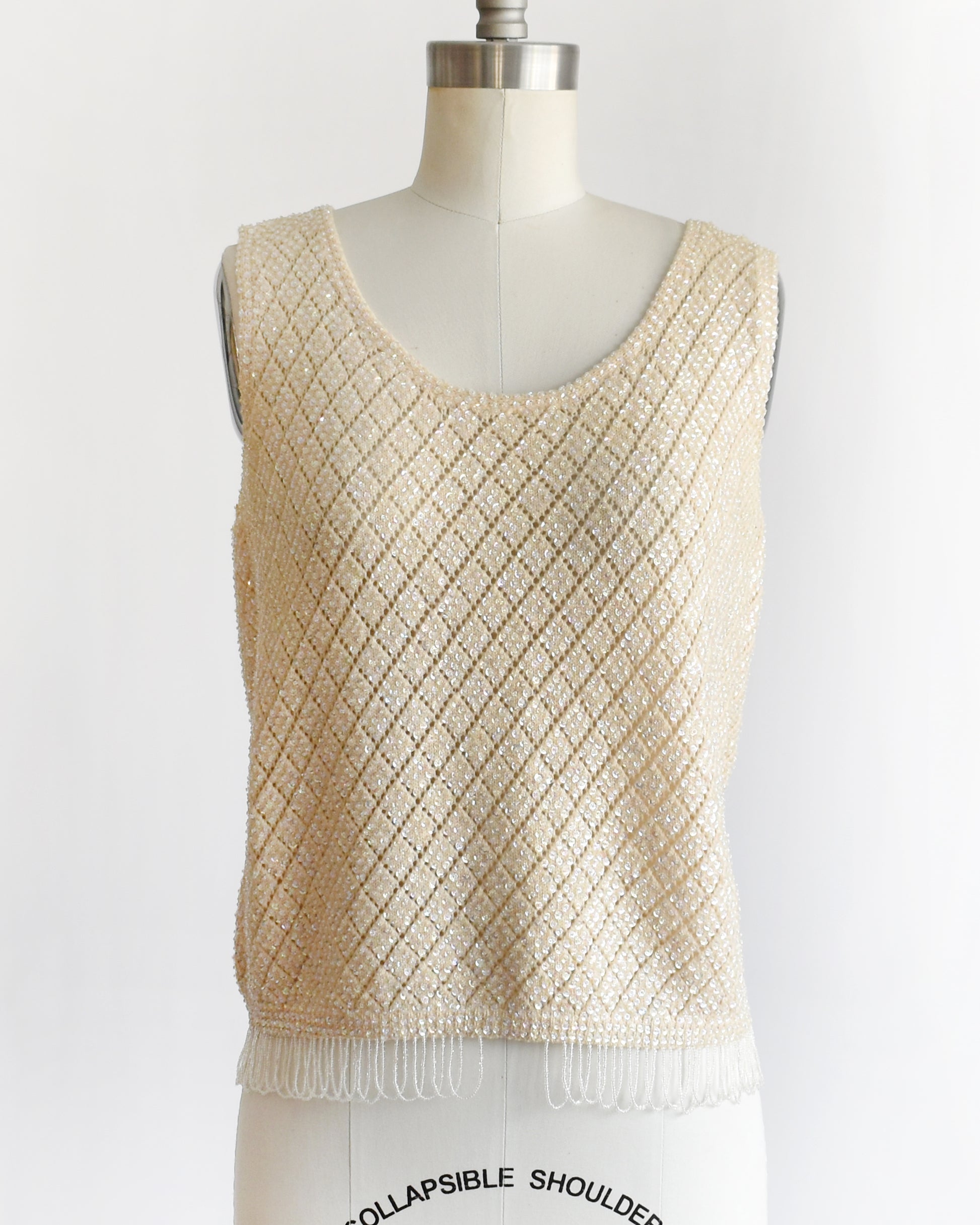 A vintage 1960s cream sequin and beaded top on a mannequin against a white background