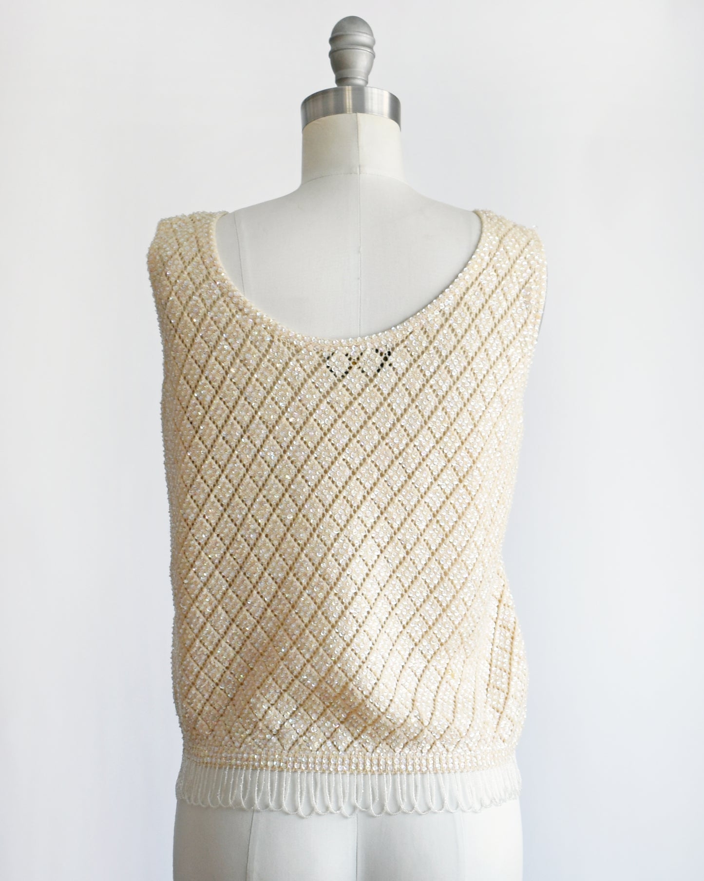 back view of a vintage 1960s cream sequin and beaded top on a mannequin against a white background