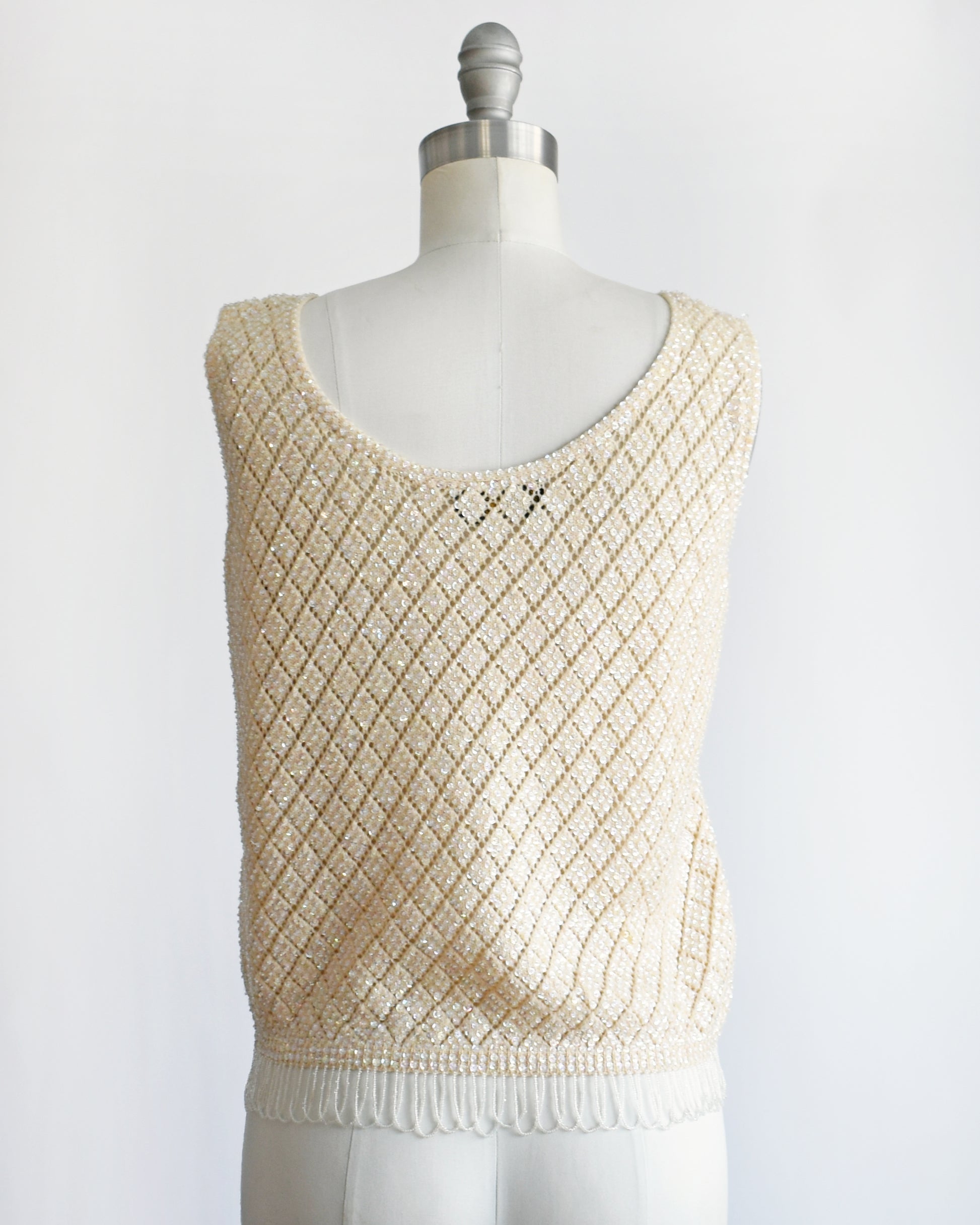 back view of a vintage 1960s cream sequin and beaded top on a mannequin against a white background