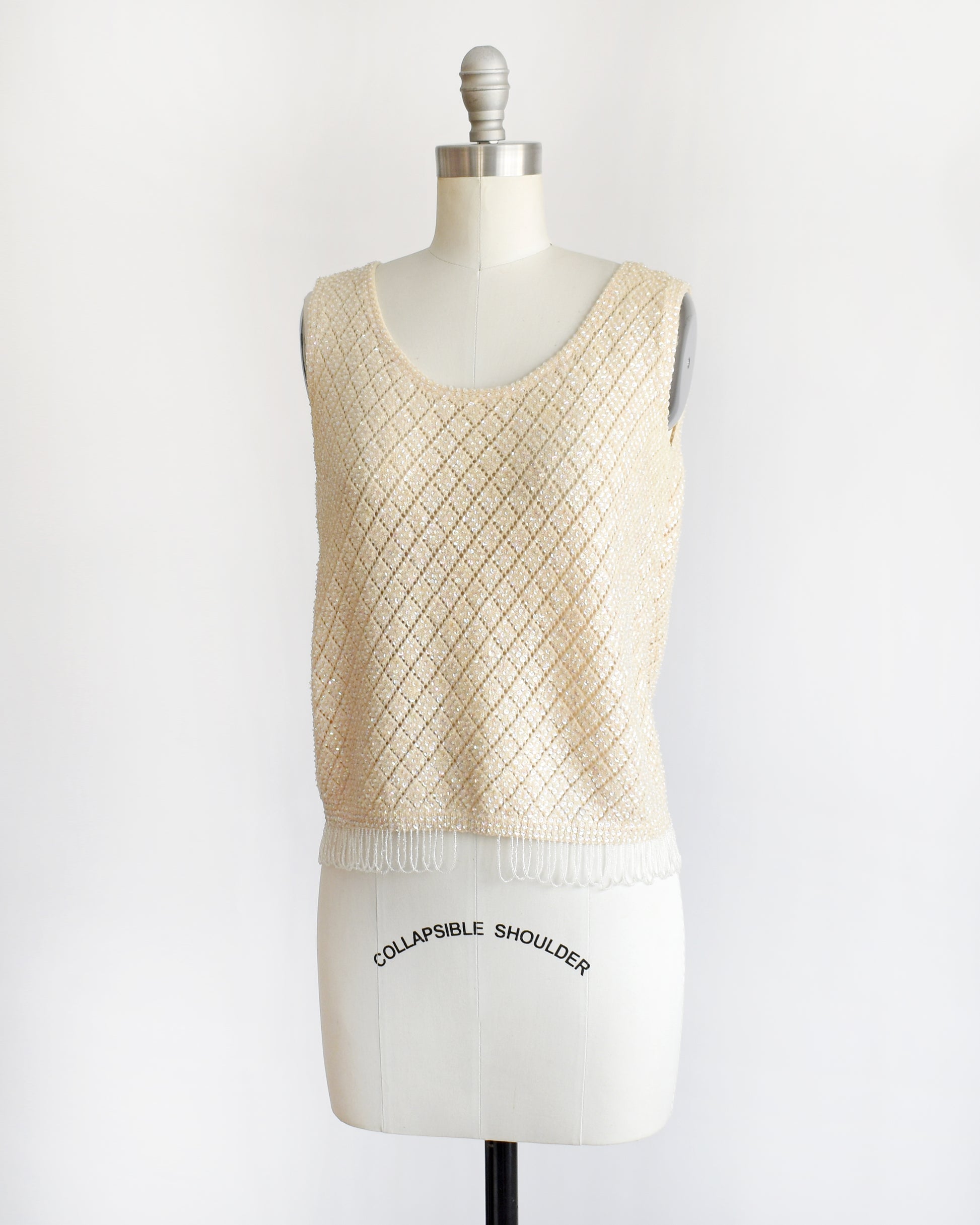 side front view of a vintage 1960s cream sequin and beaded top on a mannequin against a white background