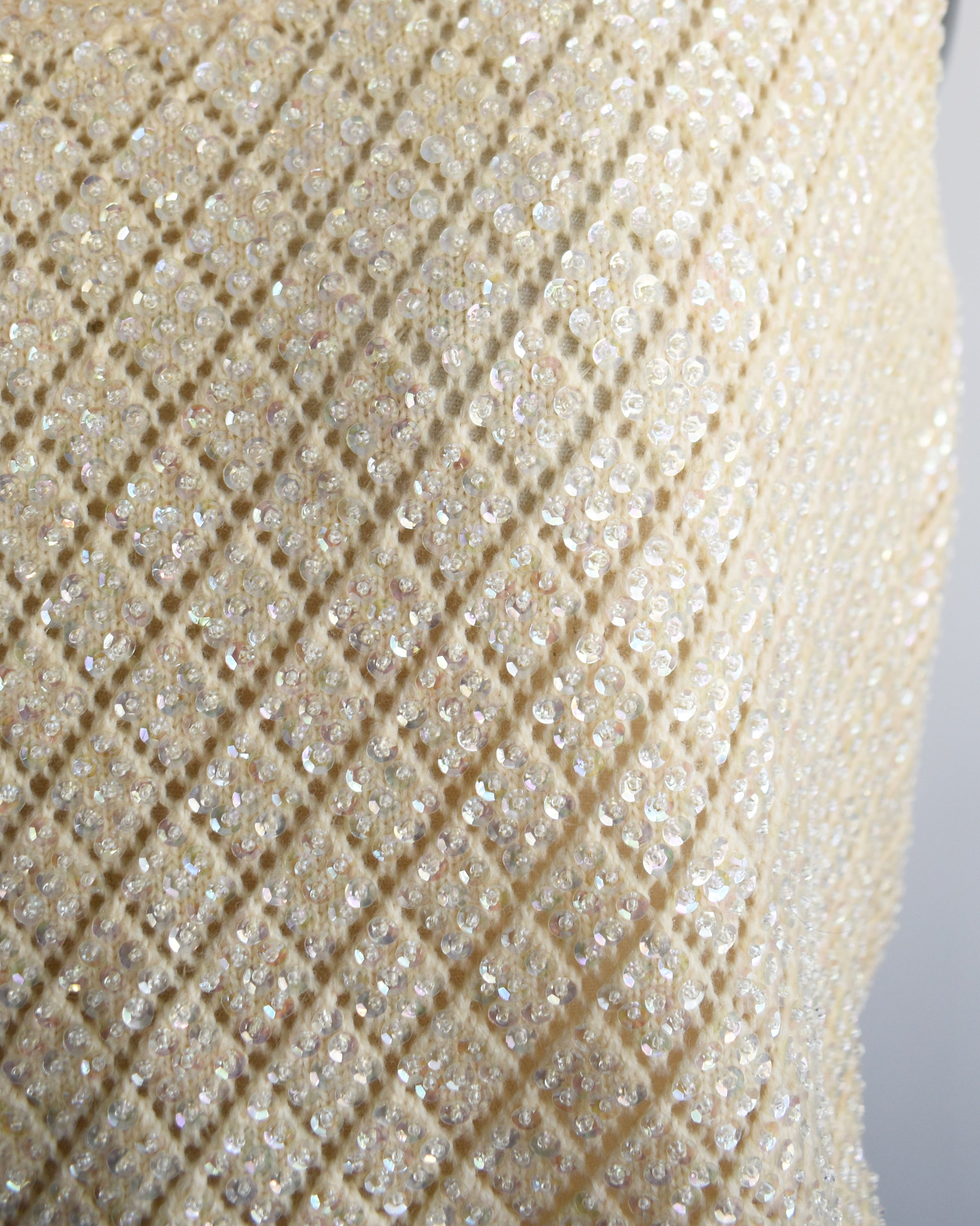 close up of a vintage 1960s cream sequin and beaded top on a mannequin against a white background