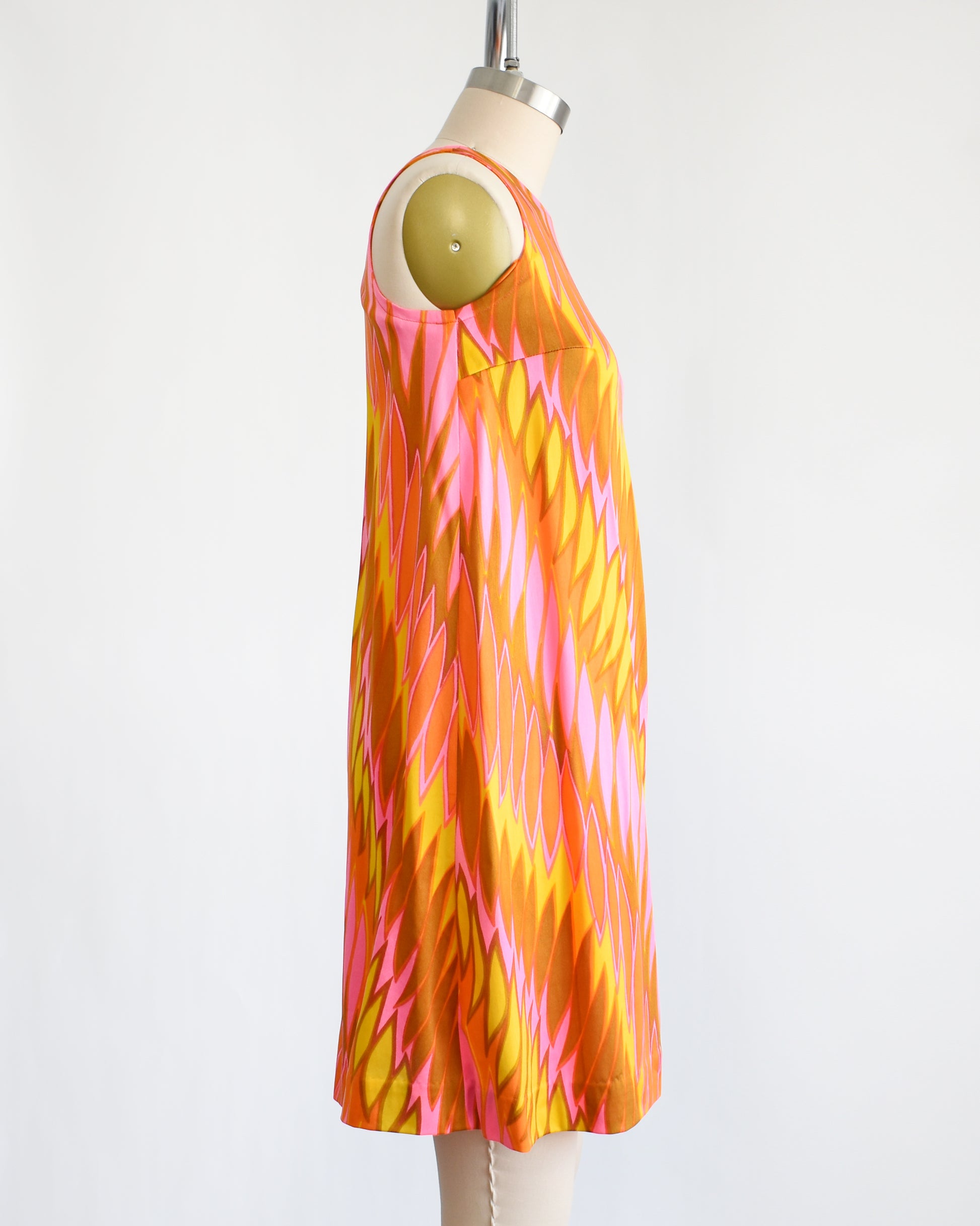 side view of a vintage 1960s mini dress that has a psychedelic print in orange, pink, yellow, and brown