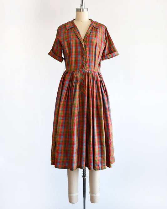 a vintage 1950s/1960s rainbow plaid silk dress on a mannequin on a white background