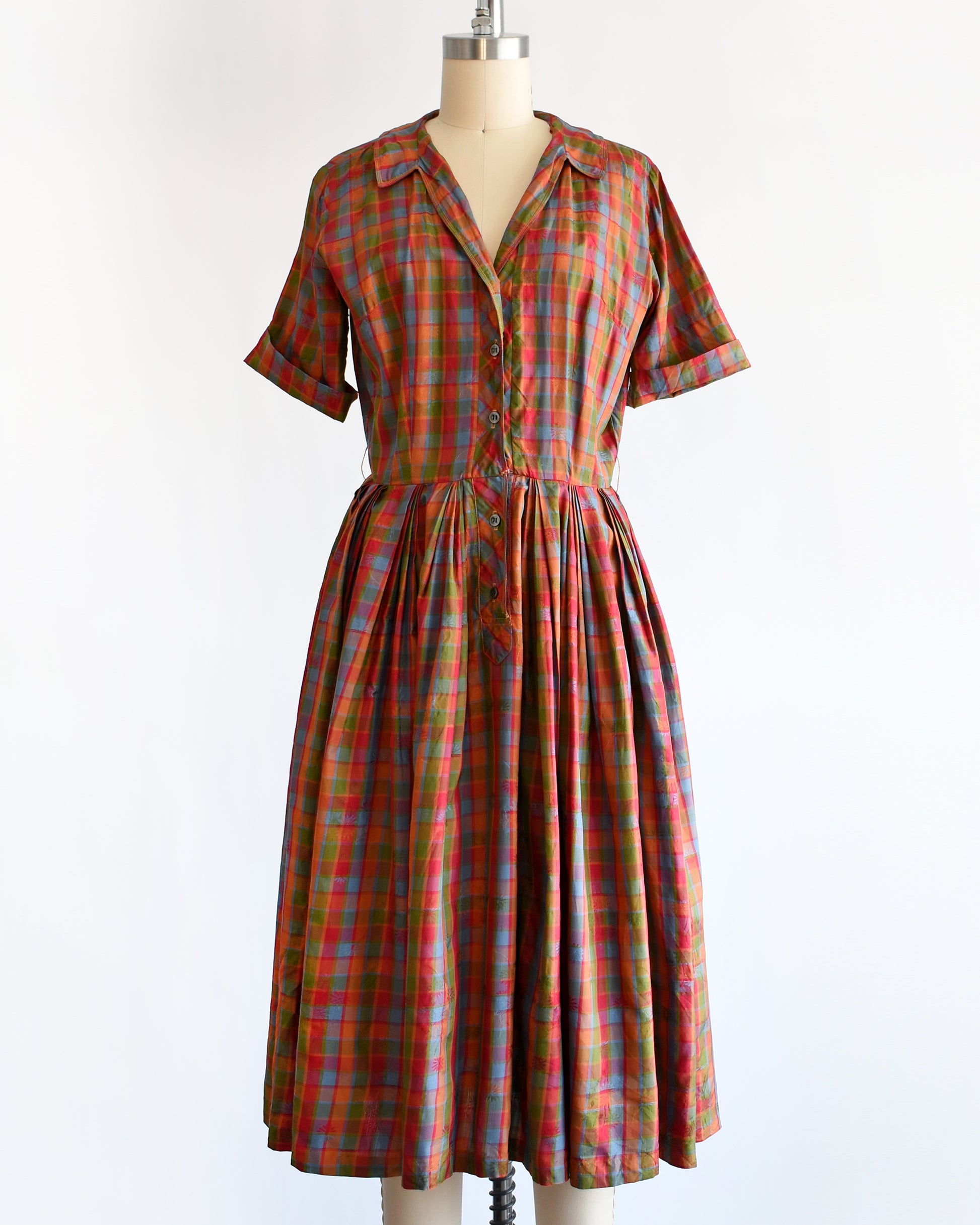 a vintage 1950s/1960s rainbow plaid silk dress on a mannequin on a white background
