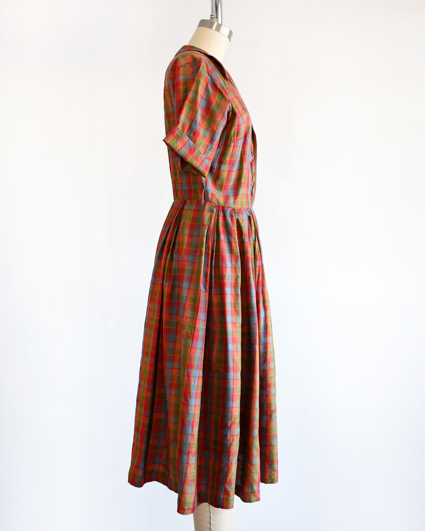 side view of a vintage 1950s/1960s rainbow plaid silk dress on a mannequin on a white background
