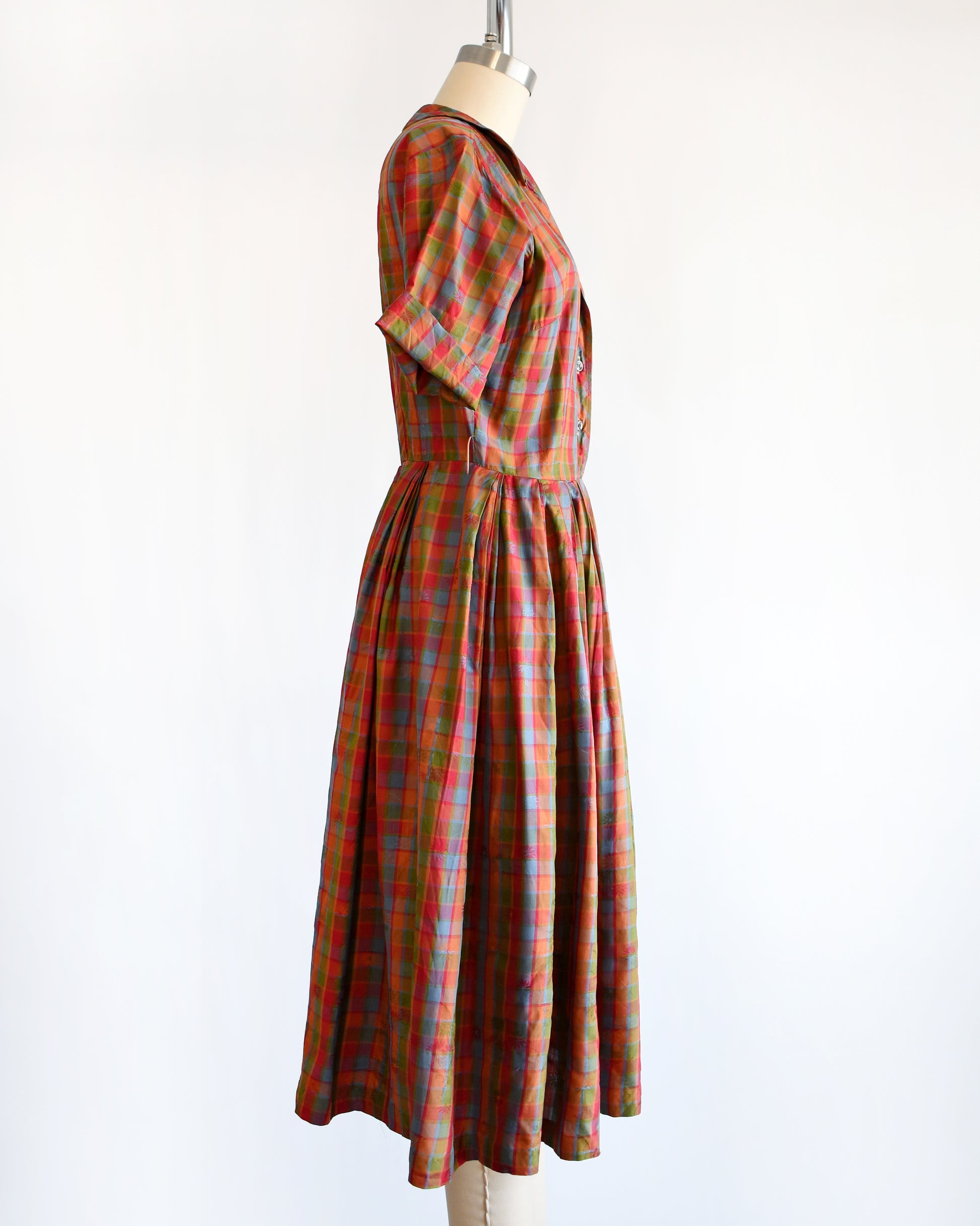 side view of a vintage 1950s/1960s rainbow plaid silk dress on a mannequin on a white background