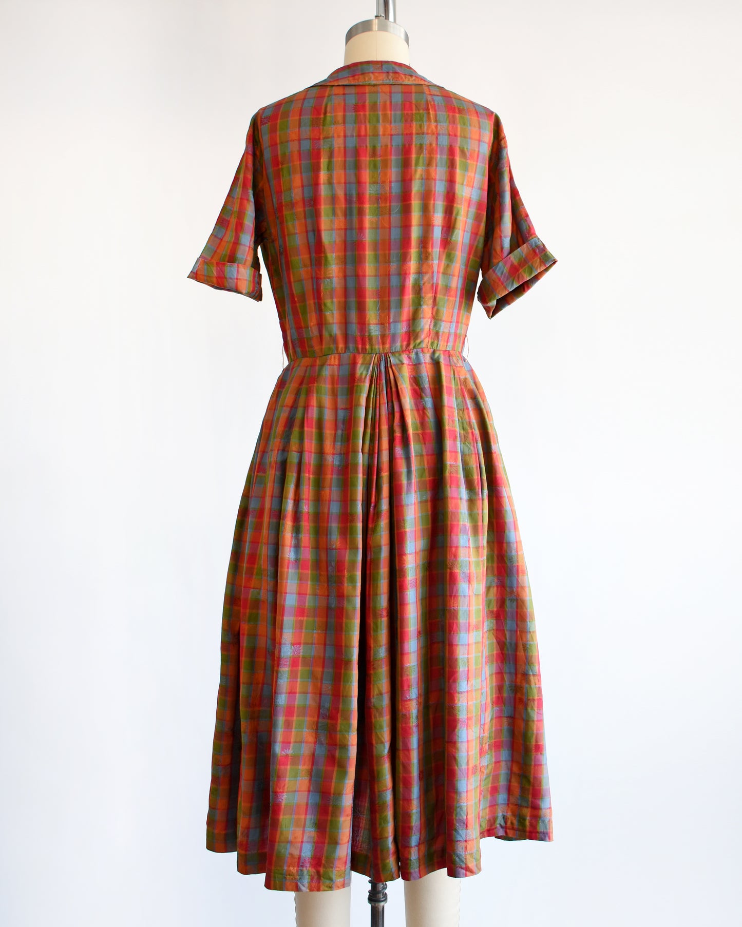 back view of a vintage 1950s/1960s rainbow plaid silk dress on a mannequin on a white background
