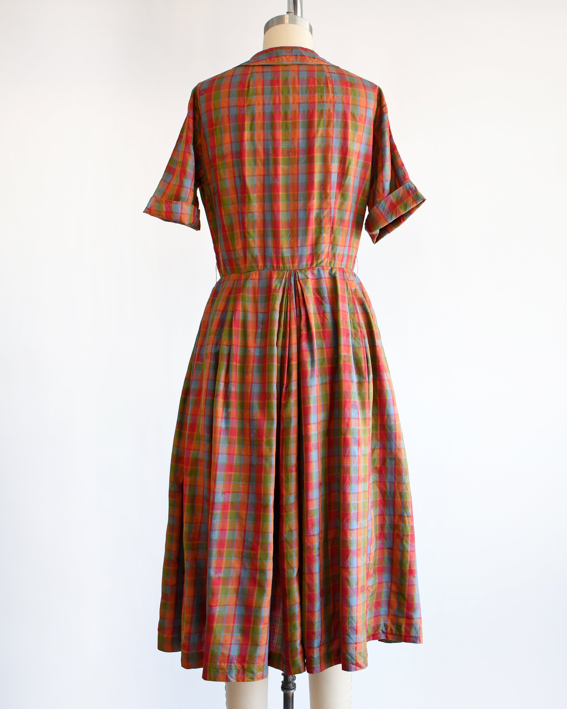 back view of a vintage 1950s/1960s rainbow plaid silk dress on a mannequin on a white background