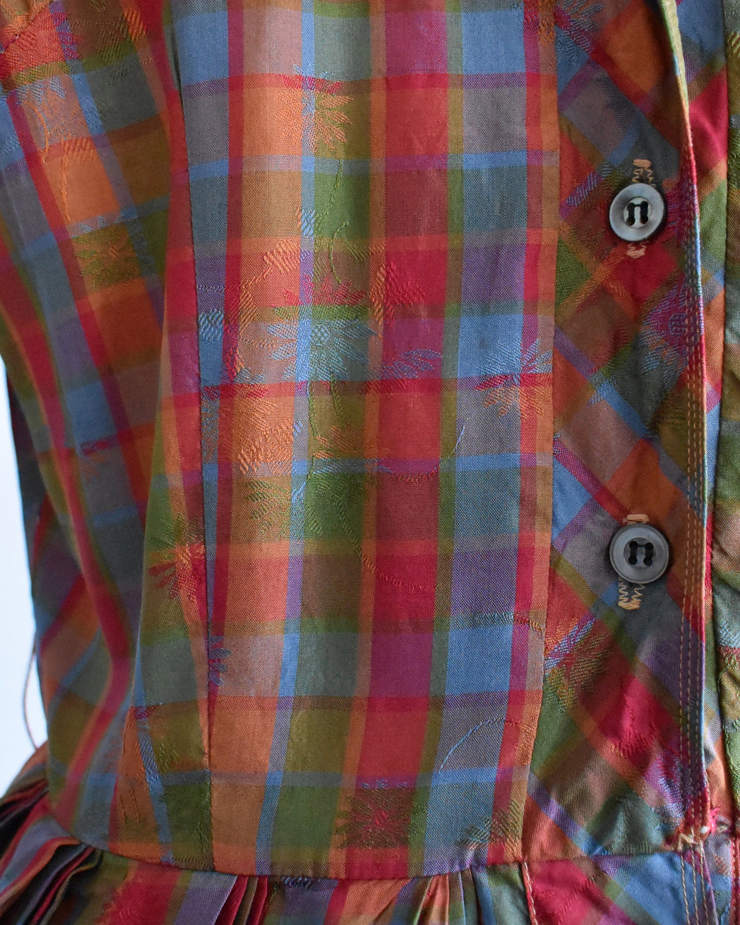 close up of the floral brocade on a vintage 1950s/1960s rainbow plaid silk dress on a mannequin on a white background