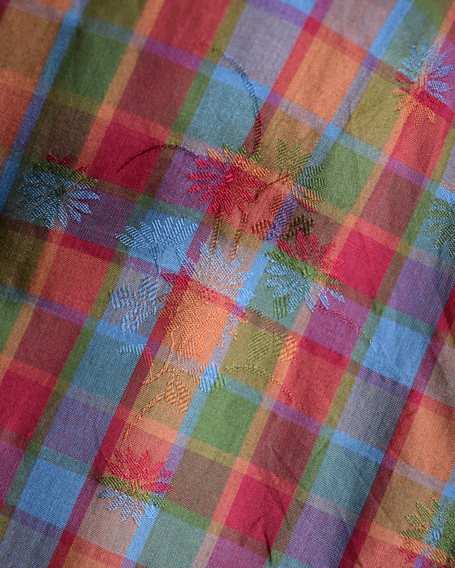 Close-up of a colorful plaid fabric with floral brocade