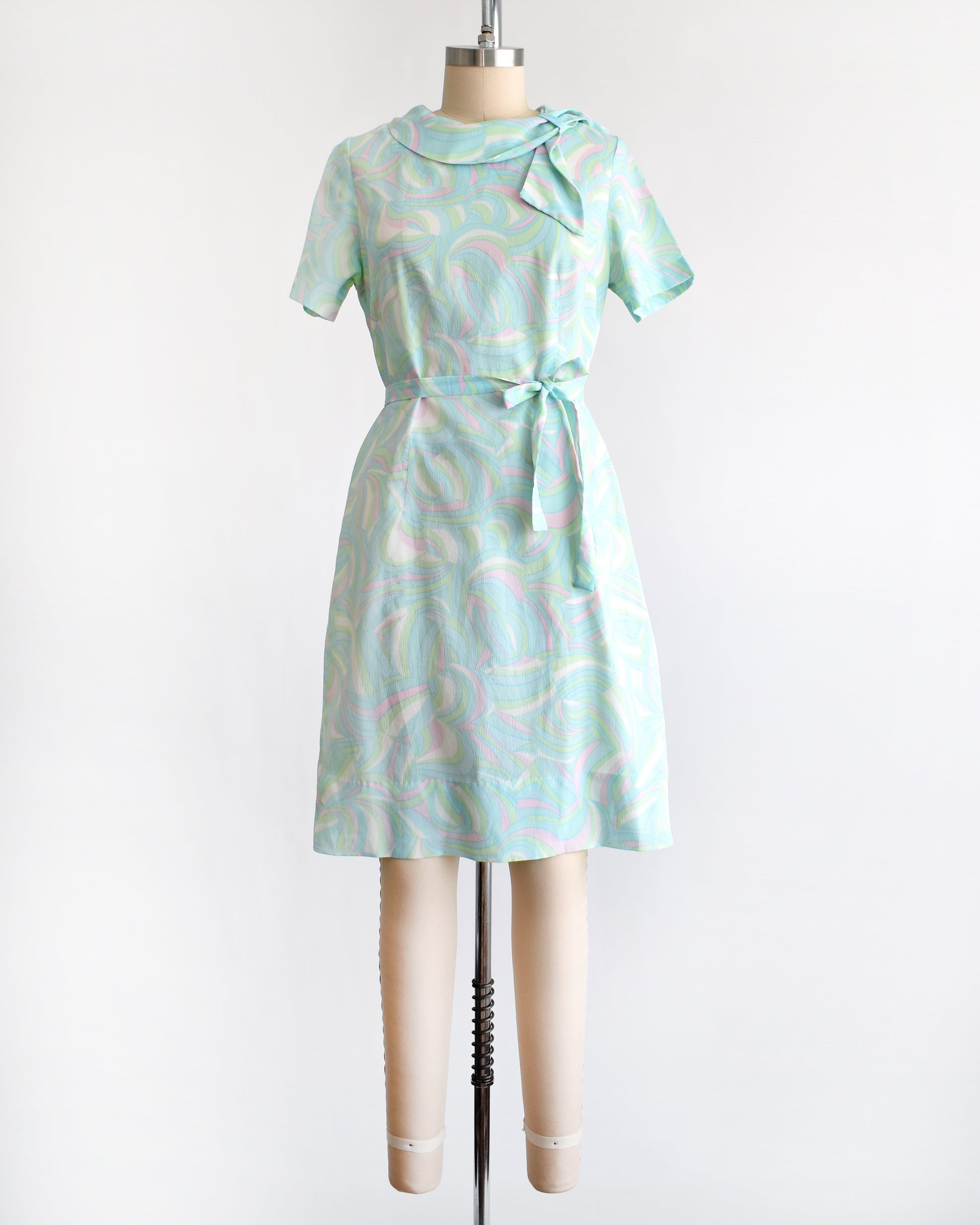 a vintage light blue dress with a swirl pattern on a mannequin against a white background
