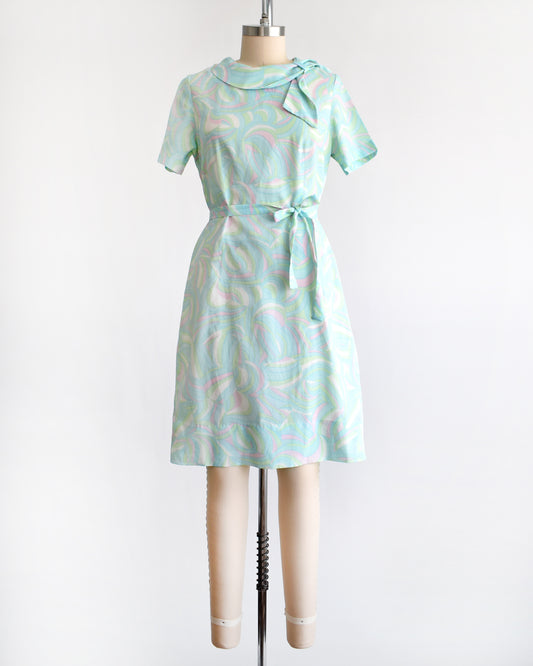 a vintage light blue dress with a swirl pattern on a mannequin against a white background