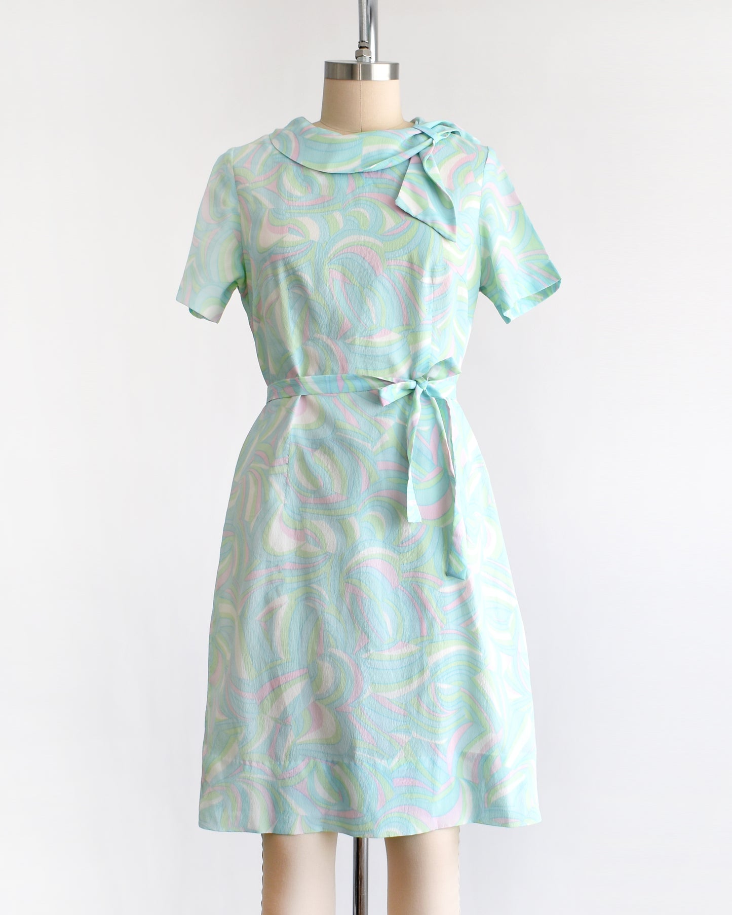 a vintage light blue dress with a swirl pattern on a mannequin against a white background