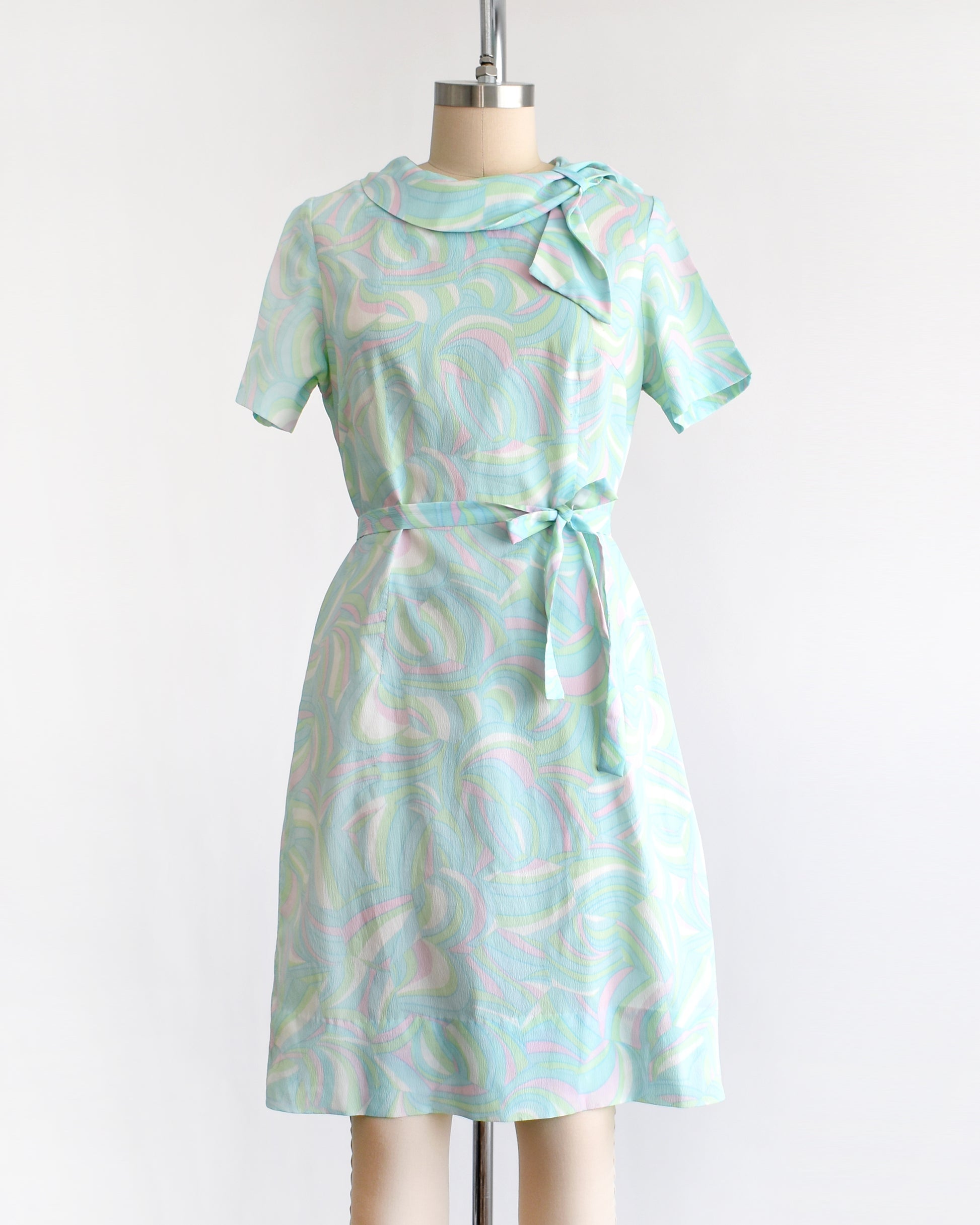 a vintage light blue dress with a swirl pattern on a mannequin against a white background