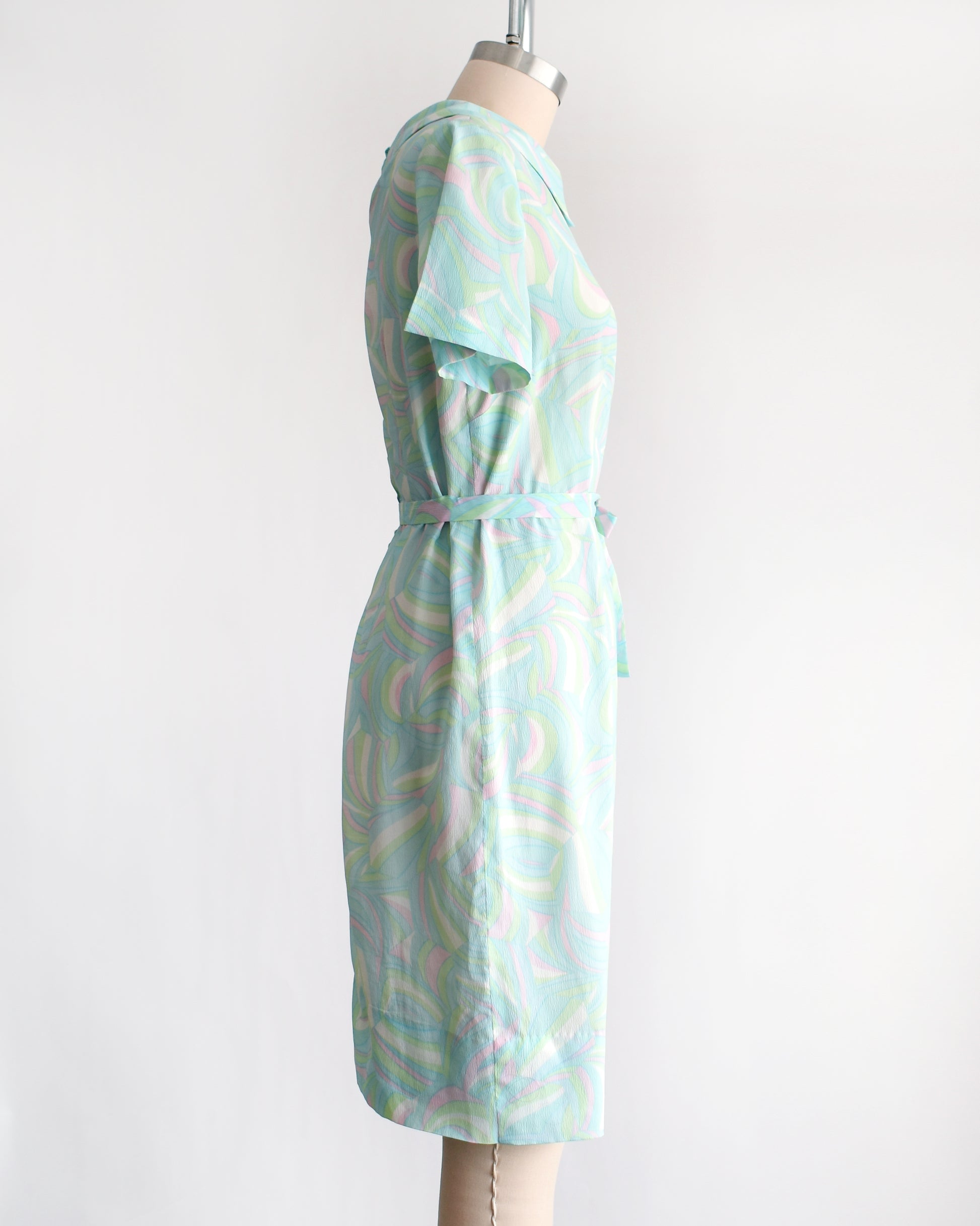 side view of a vintage light blue dress with a swirl pattern on a mannequin against a white background