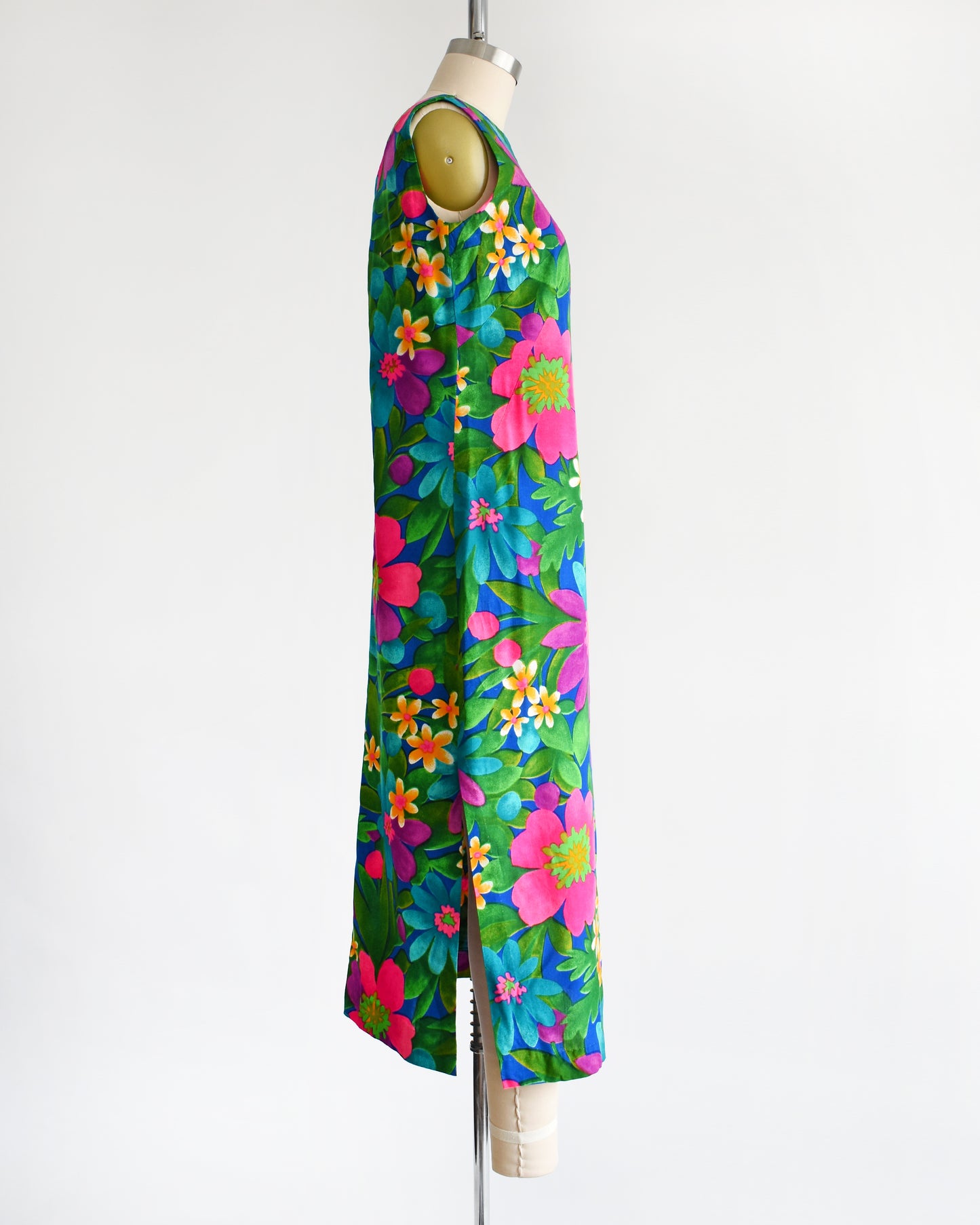 side view of a vintage 1960s colorful floral dress on a mannequin against a white background
