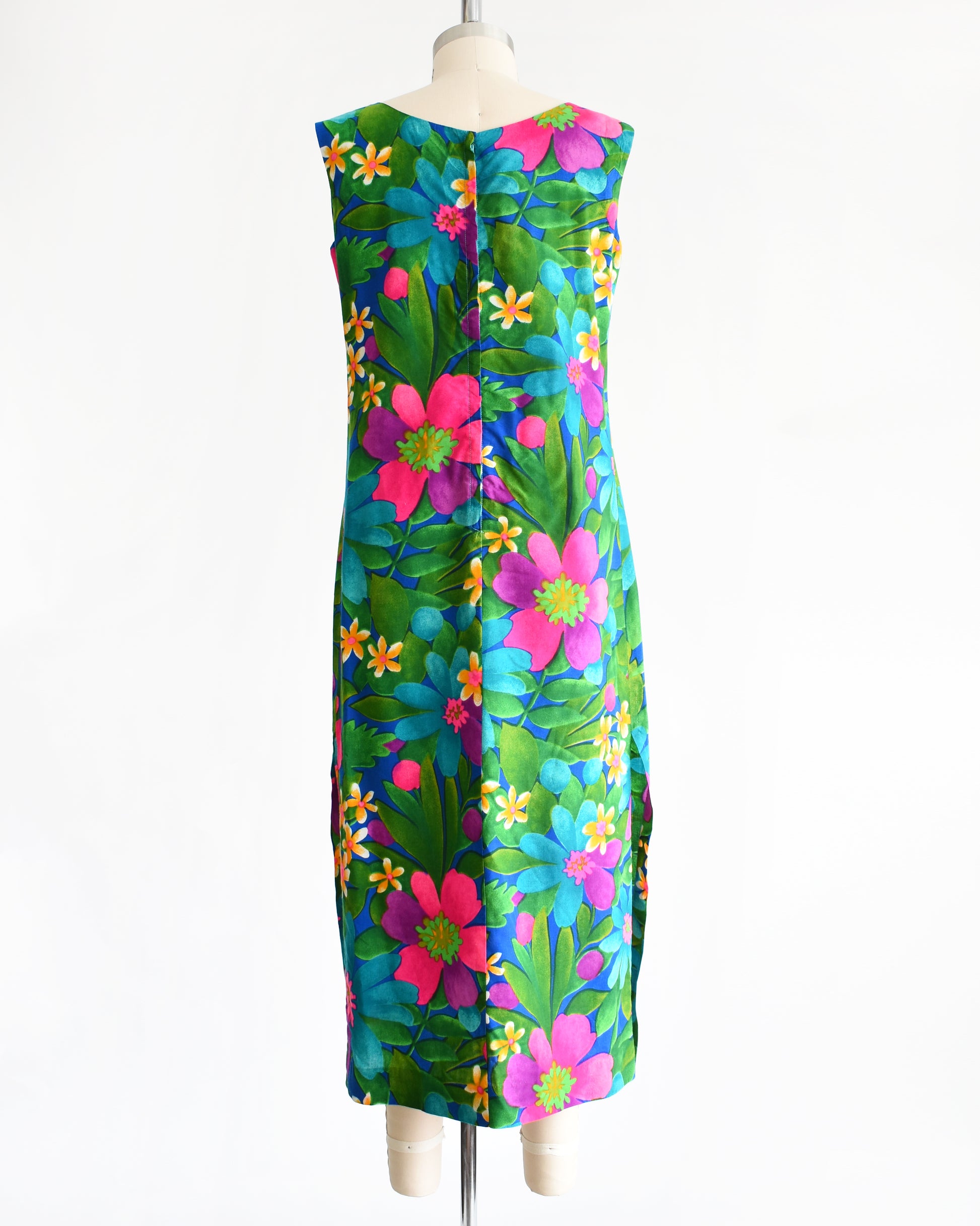 back view of a vintage 1960s colorful floral dress on a mannequin against a white background