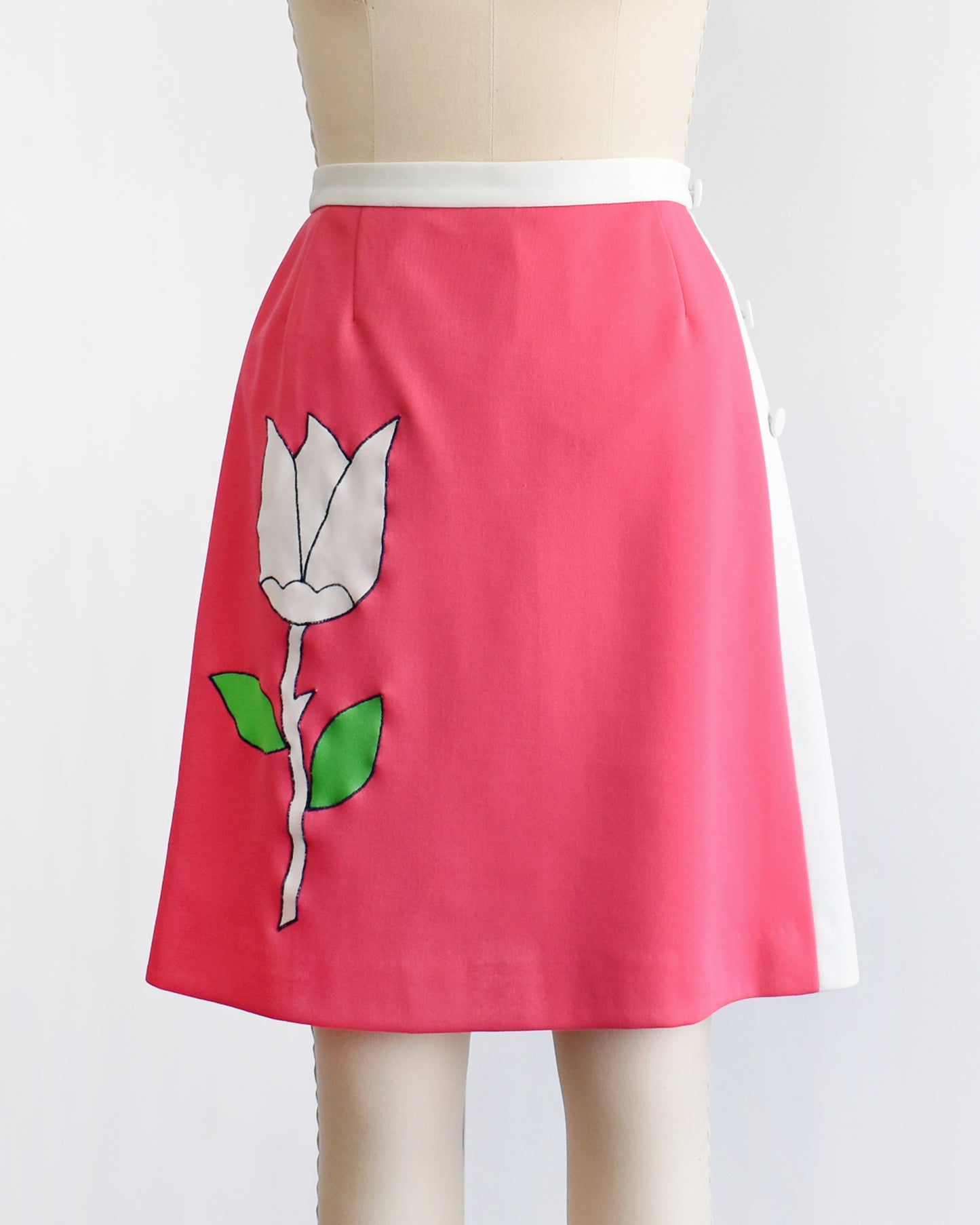 a vintage 1970s pink skirt/skort with a white tulip design on a mannequin against a white background