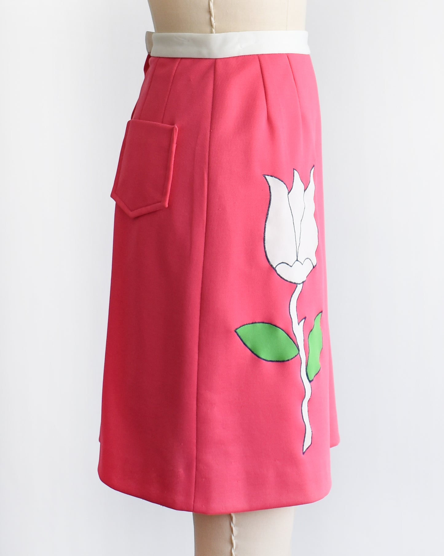 side view of a vintage 1970s pink skirt/skort with a white tulip design on a mannequin against a white background