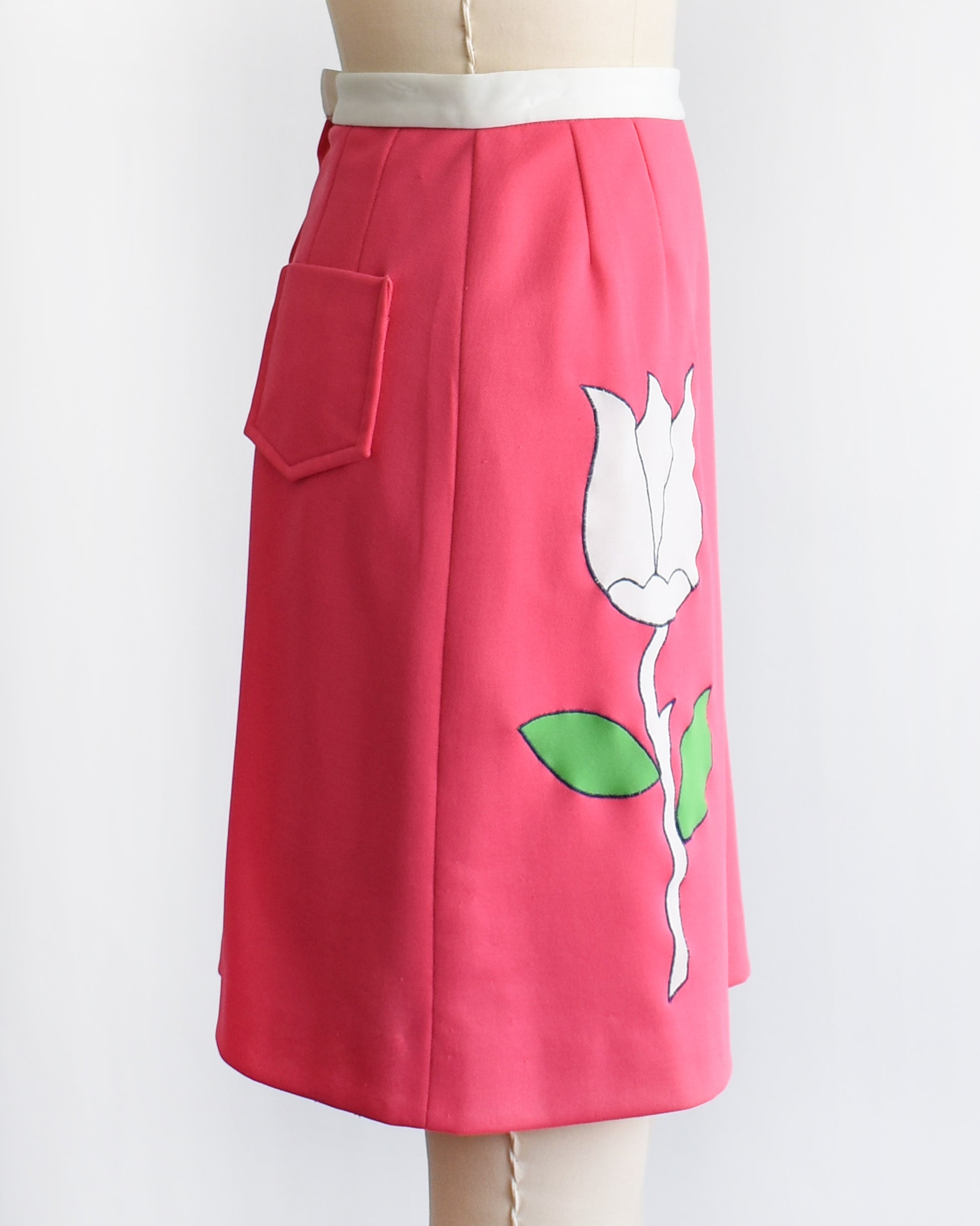 side view of a vintage 1970s pink skirt/skort with a white tulip design on a mannequin against a white background