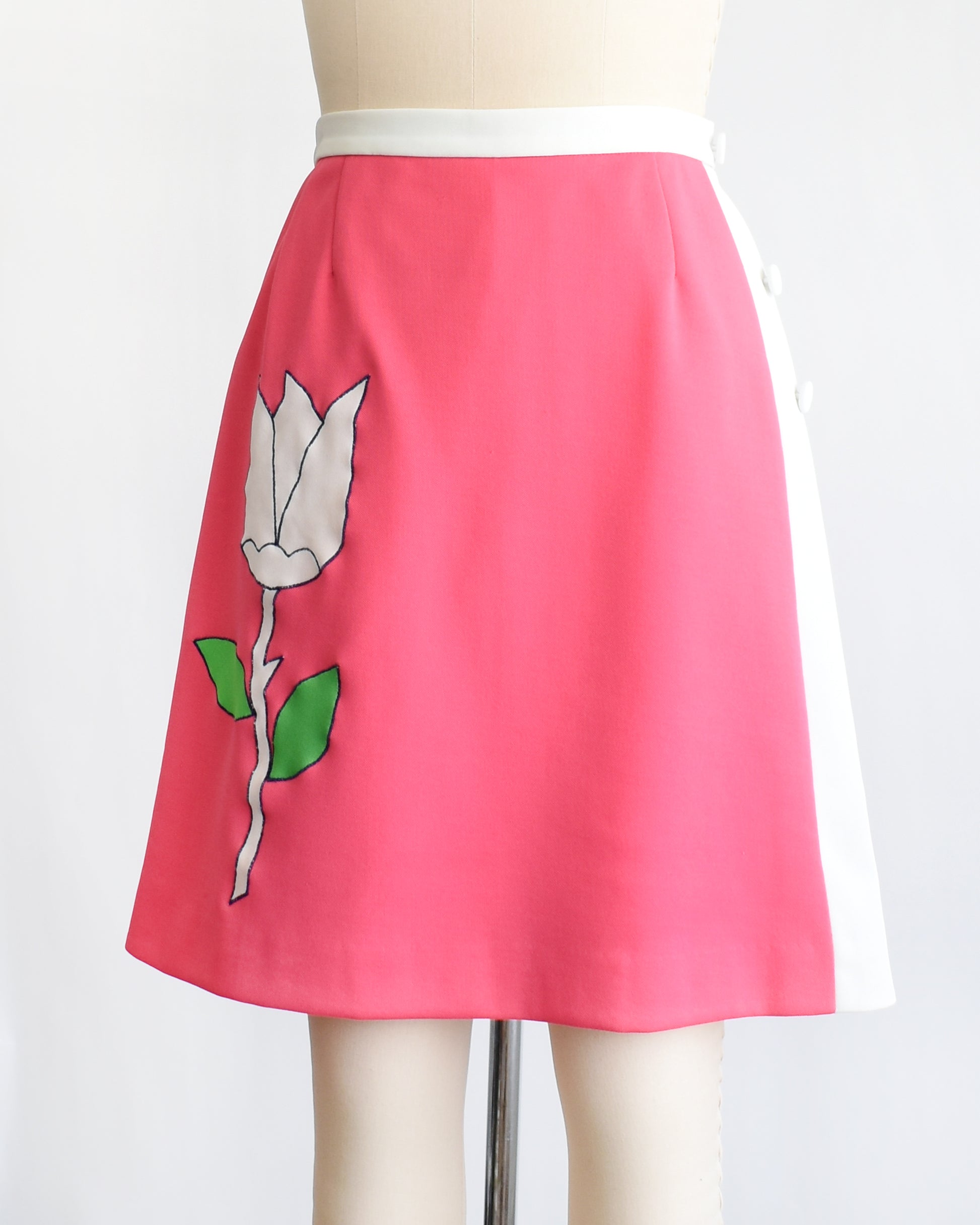 side front view of a vintage 1970s pink skirt/skort with a white tulip design on a mannequin against a white background