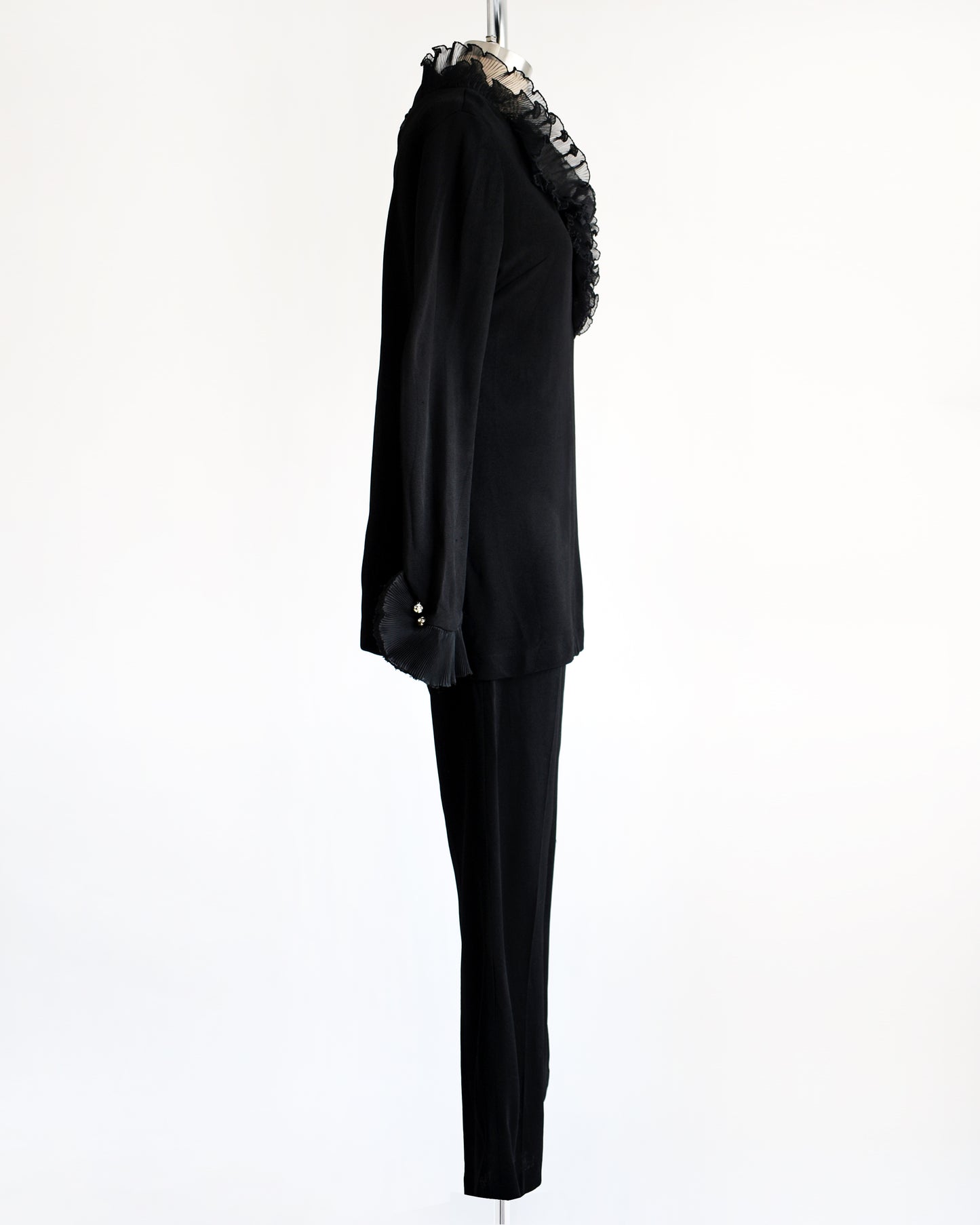 side view of a vintage 1970s black ruffled pant set with decorative rhinestone buttons