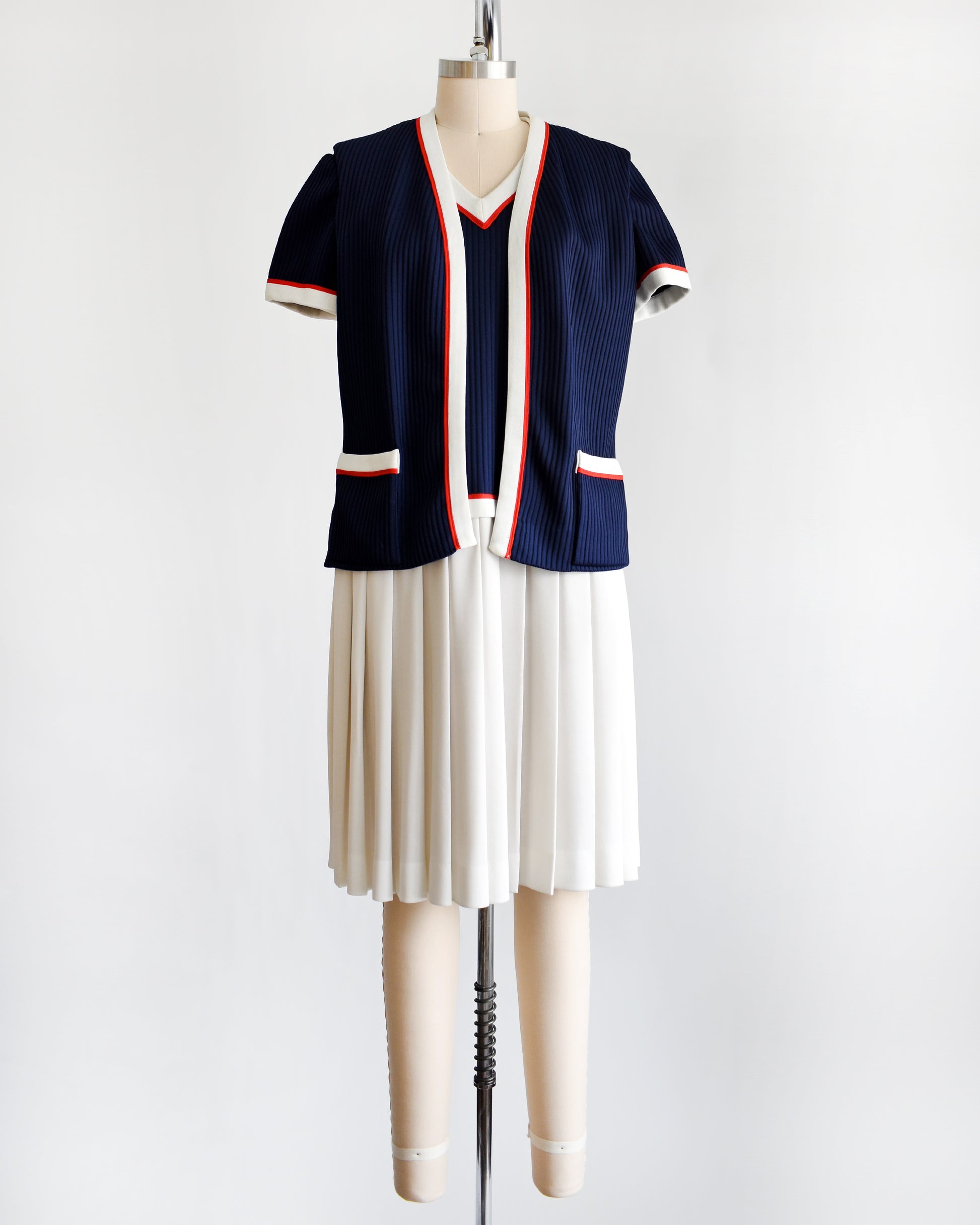 a vintage 1970s navy and white dress set that has red trim and a white skirt on a mannequin on a white background