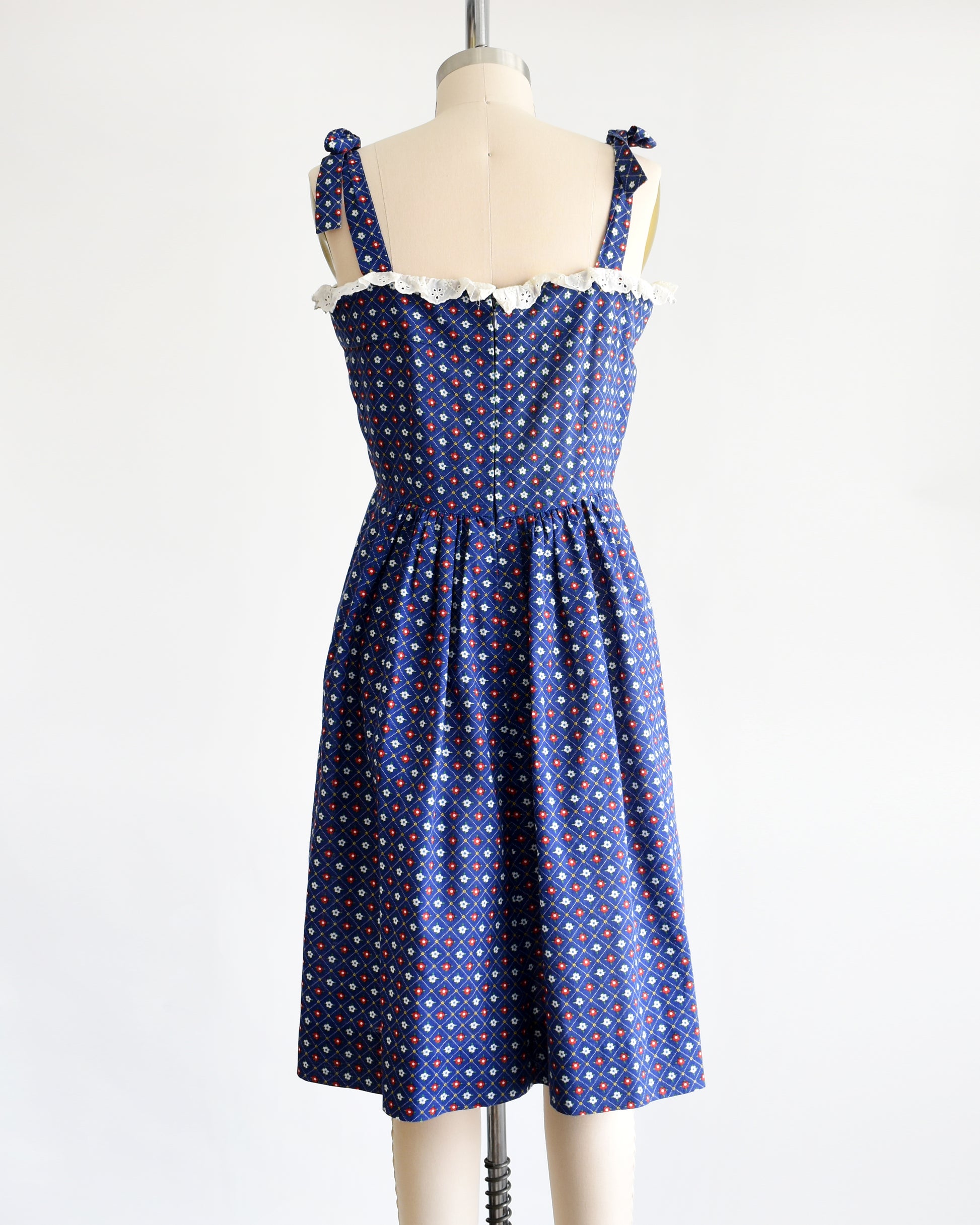 back view of a vintage 1970s navy blue floral sundress  on a dress form