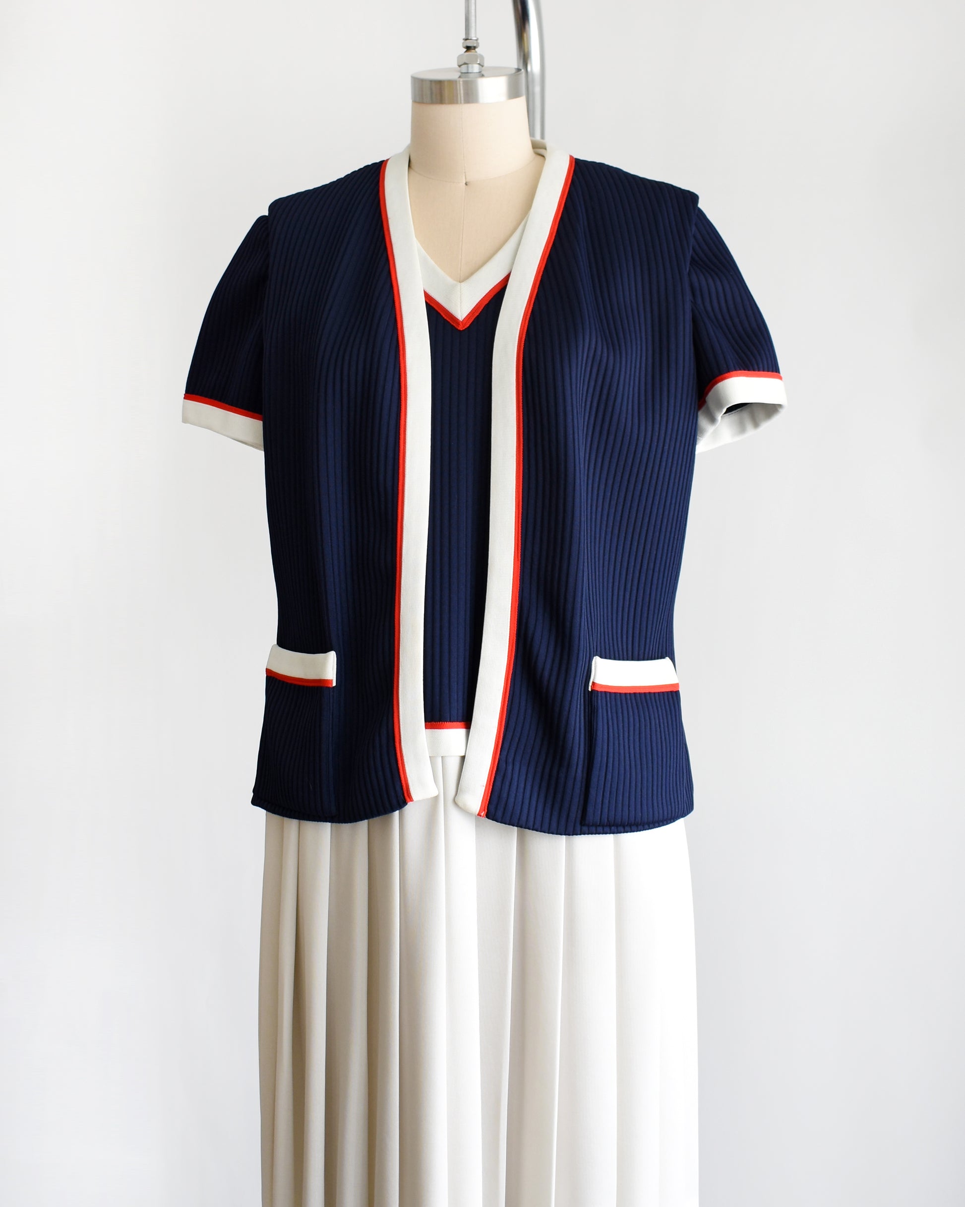 side view of a vintage 1970s navy and white dress set that has red trim and a white skirt on a mannequin on a white background