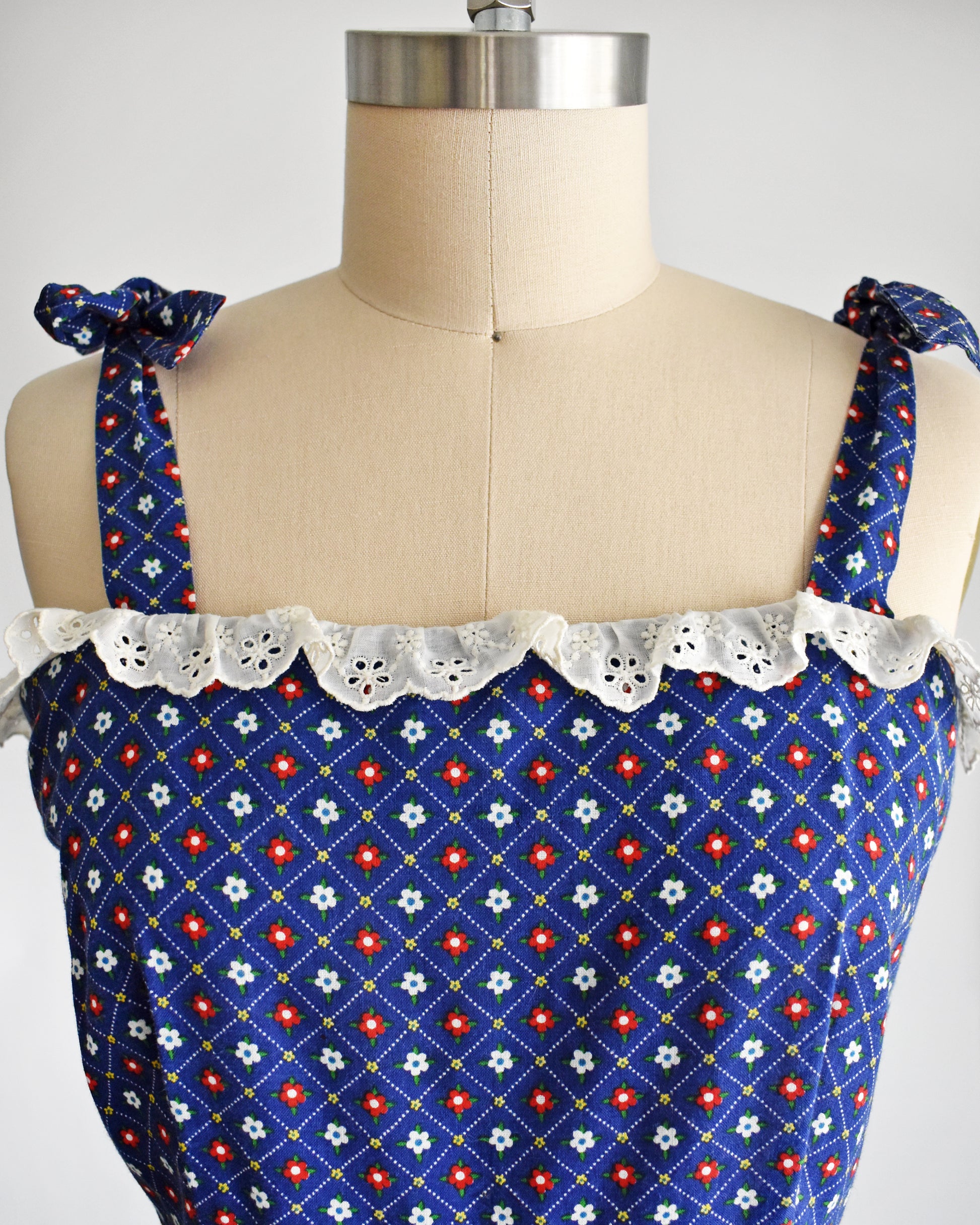 close up of the bodice on a a vintage 1970s navy blue floral sundress on a dress form