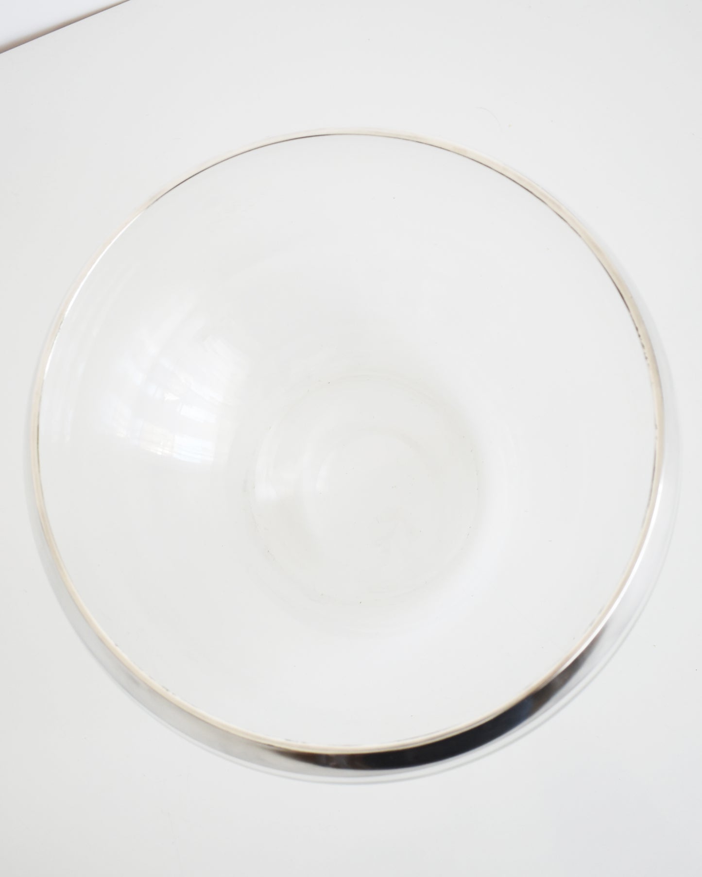 overhead shot of a vintage silver rim clear glass punch bowl on a white background