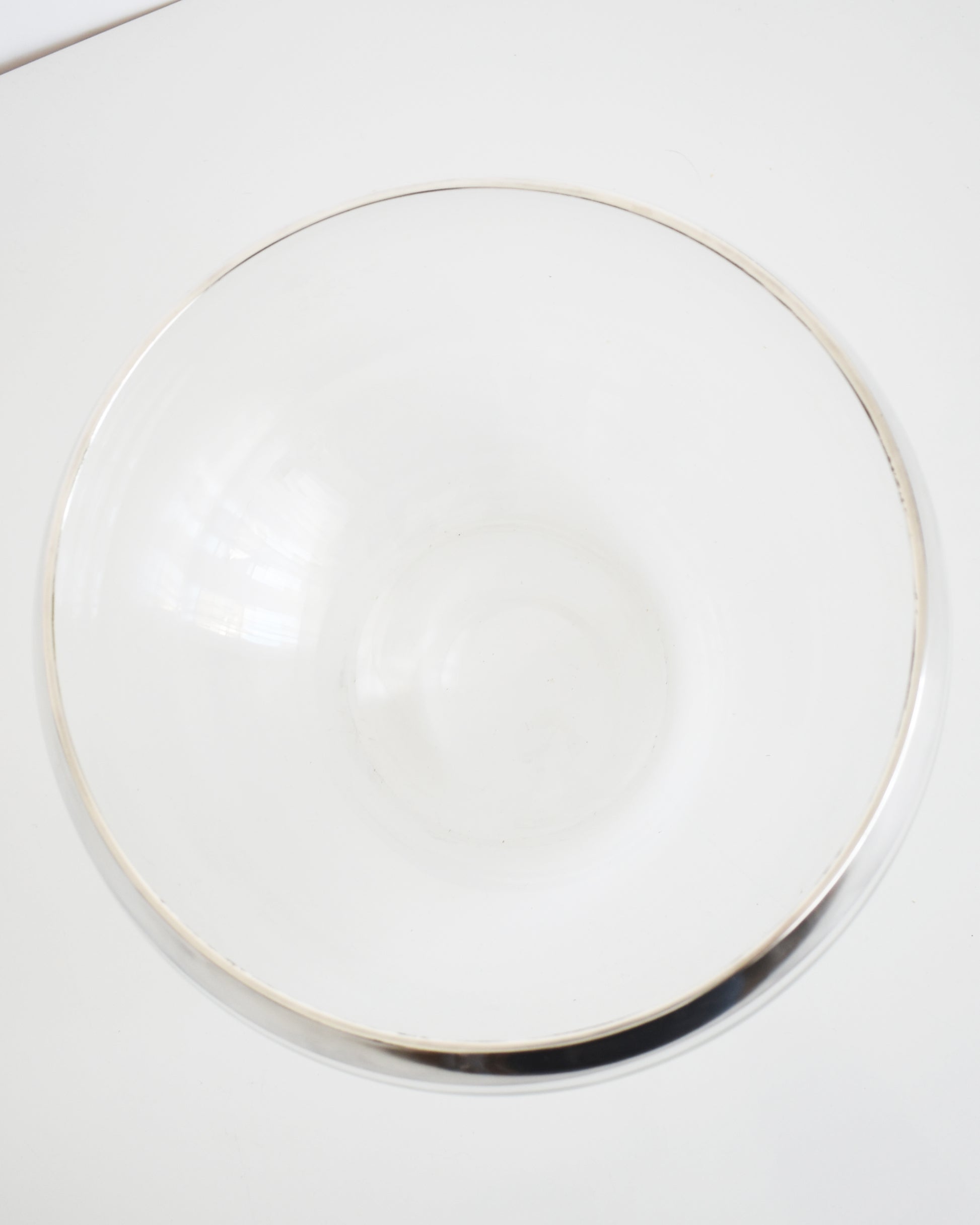 overhead shot of a vintage silver rim clear glass punch bowl on a white background