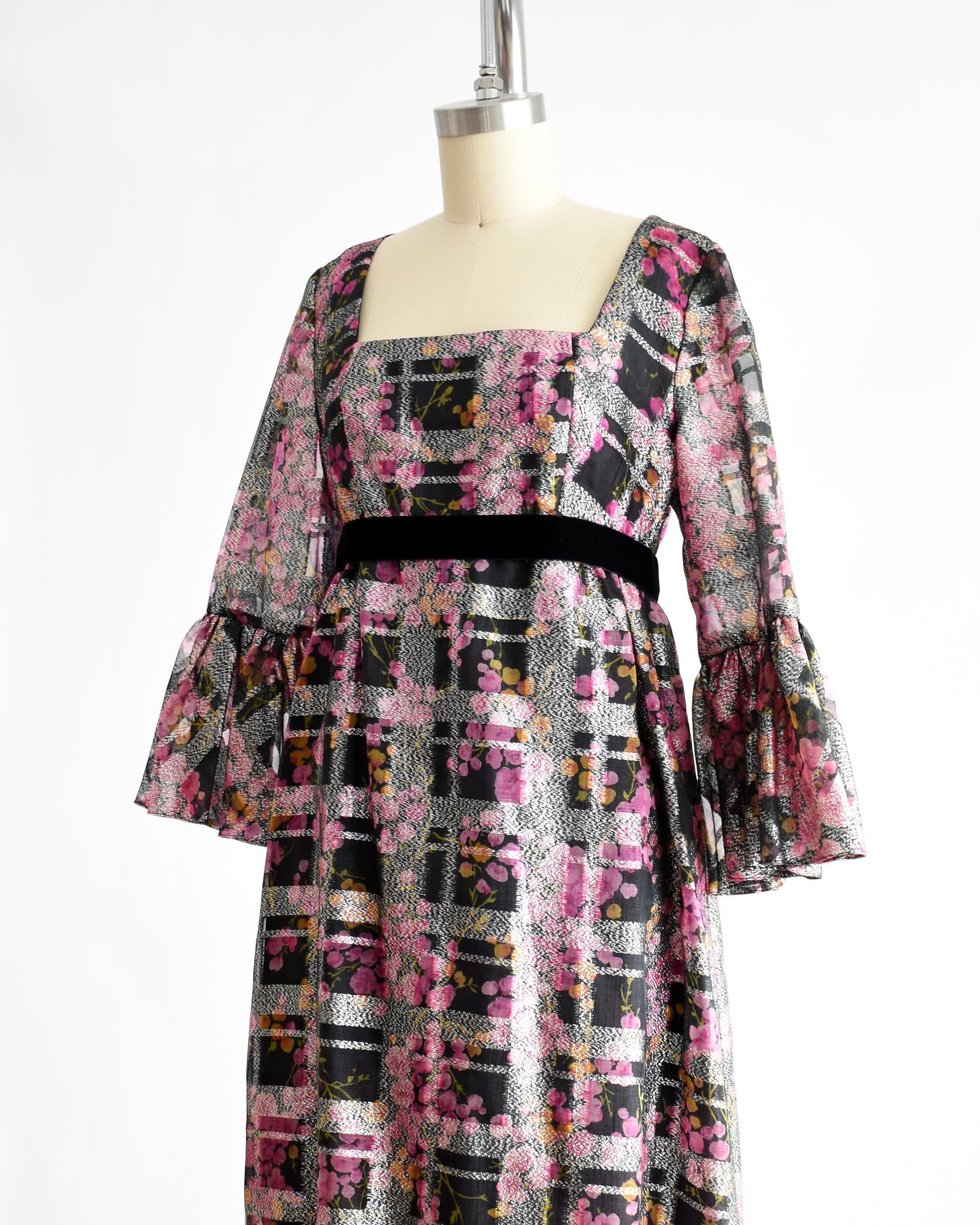 side view of a vintage 1970s pink and black floral Victor Costa dress on a mannequin against a white background