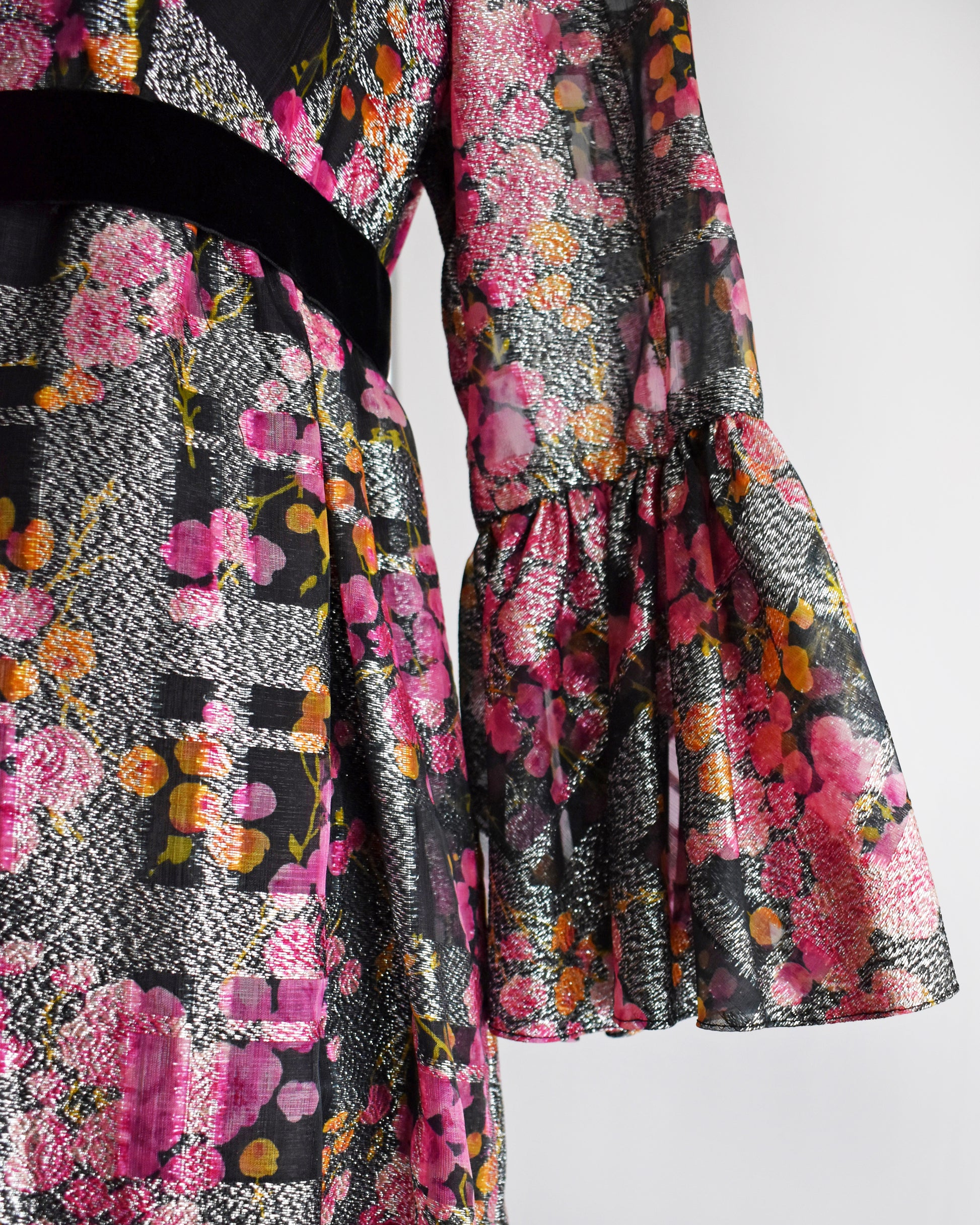 close up of the bells sleeve on a vintage 1970s pink and black floral Victor Costa dress on a mannequin against a white background