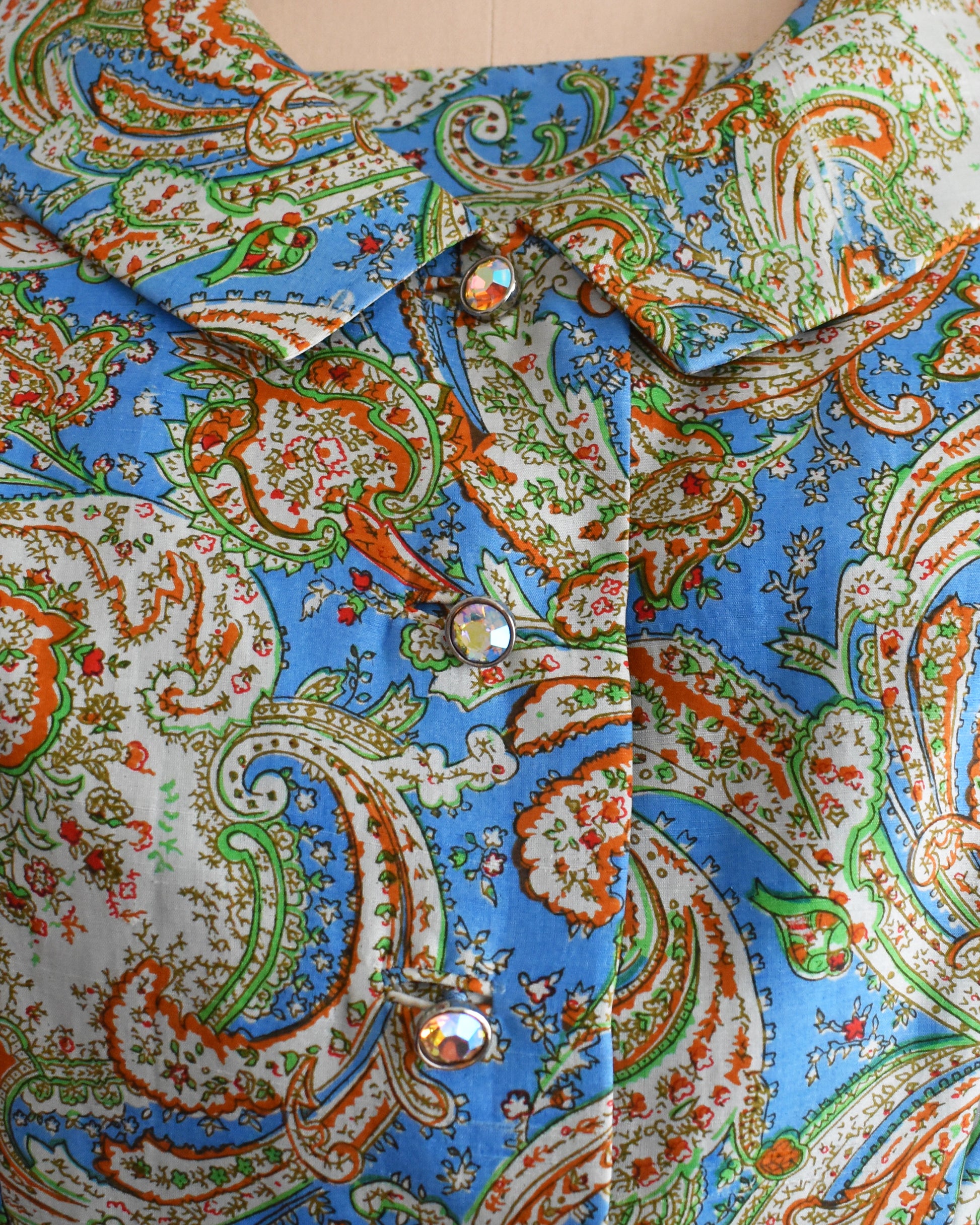 a close up version of the jacket, which shows the paisley print, and rhinestone buttons