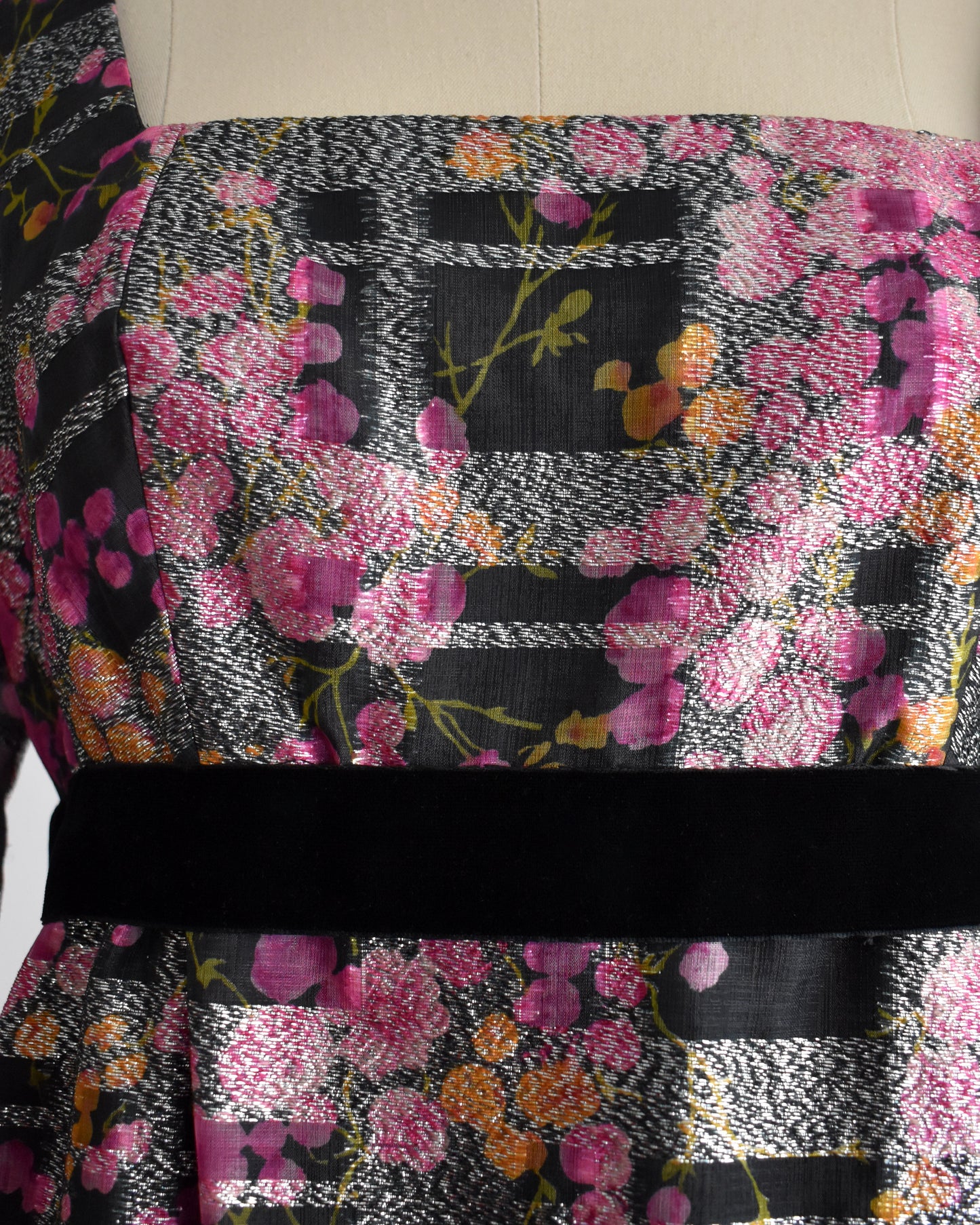close up of the bodice of a vintage 1970s pink and black floral Victor Costa dress on a mannequin against a white background