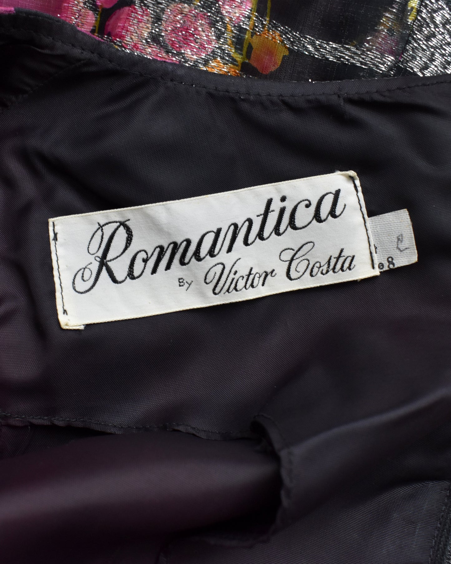 Label with 'Romantica by Victor Costa' on a dark fabric background