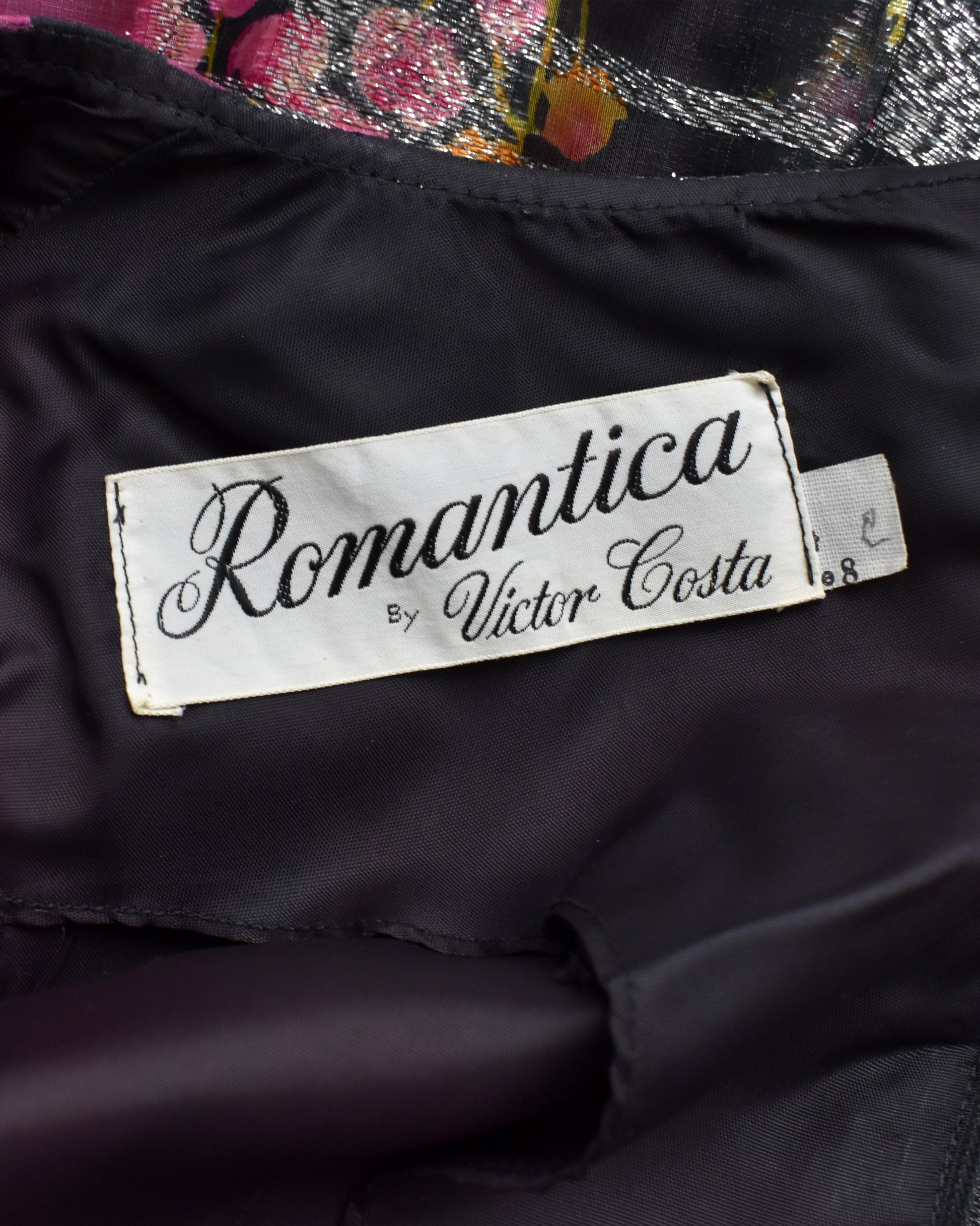 Label with 'Romantica by Victor Costa' on a dark fabric background