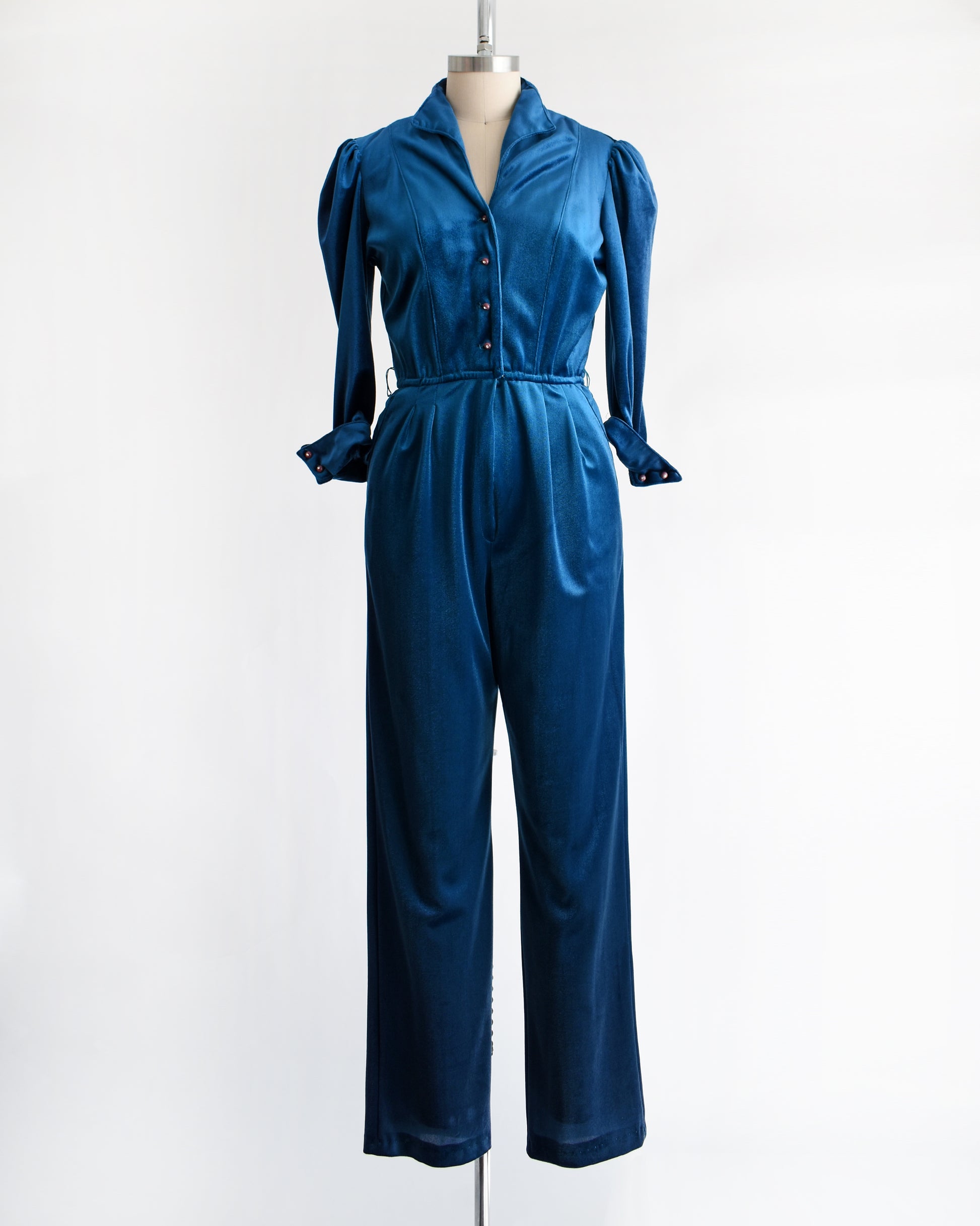 a vintage 1970s blue velour jumpsuit on a mannequin against a white background