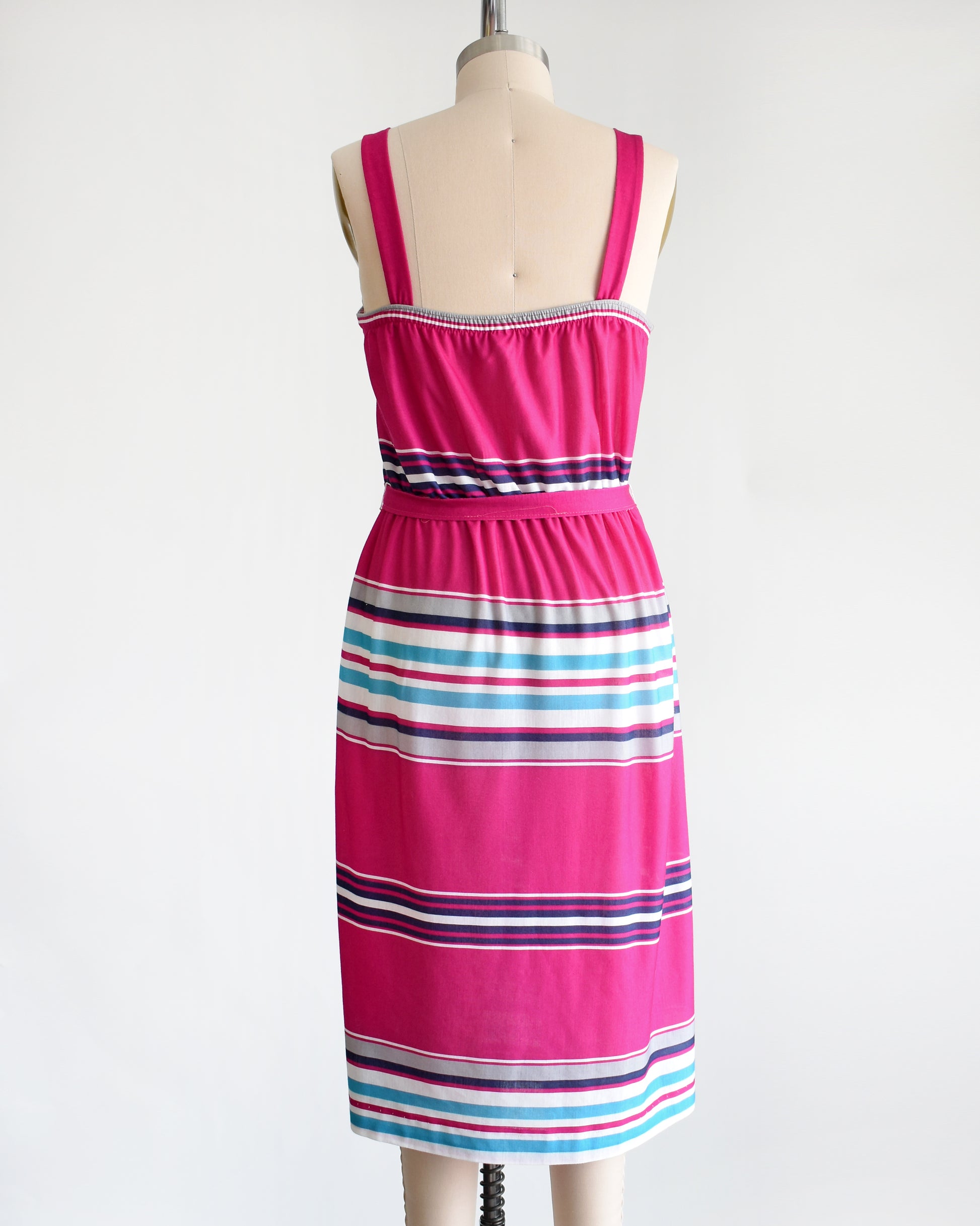 back view of a vintage 1970s/1980s sundress that  has horizontal stripes in magenta, light blue, navy blue, gray and white, along with a matching belt.