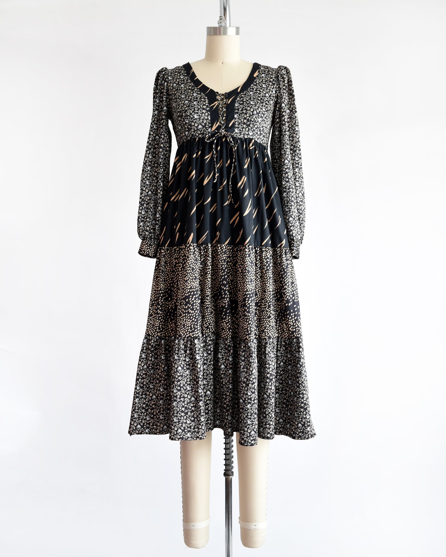 a vintage 1970s black floral dress on a mannequin against a white background