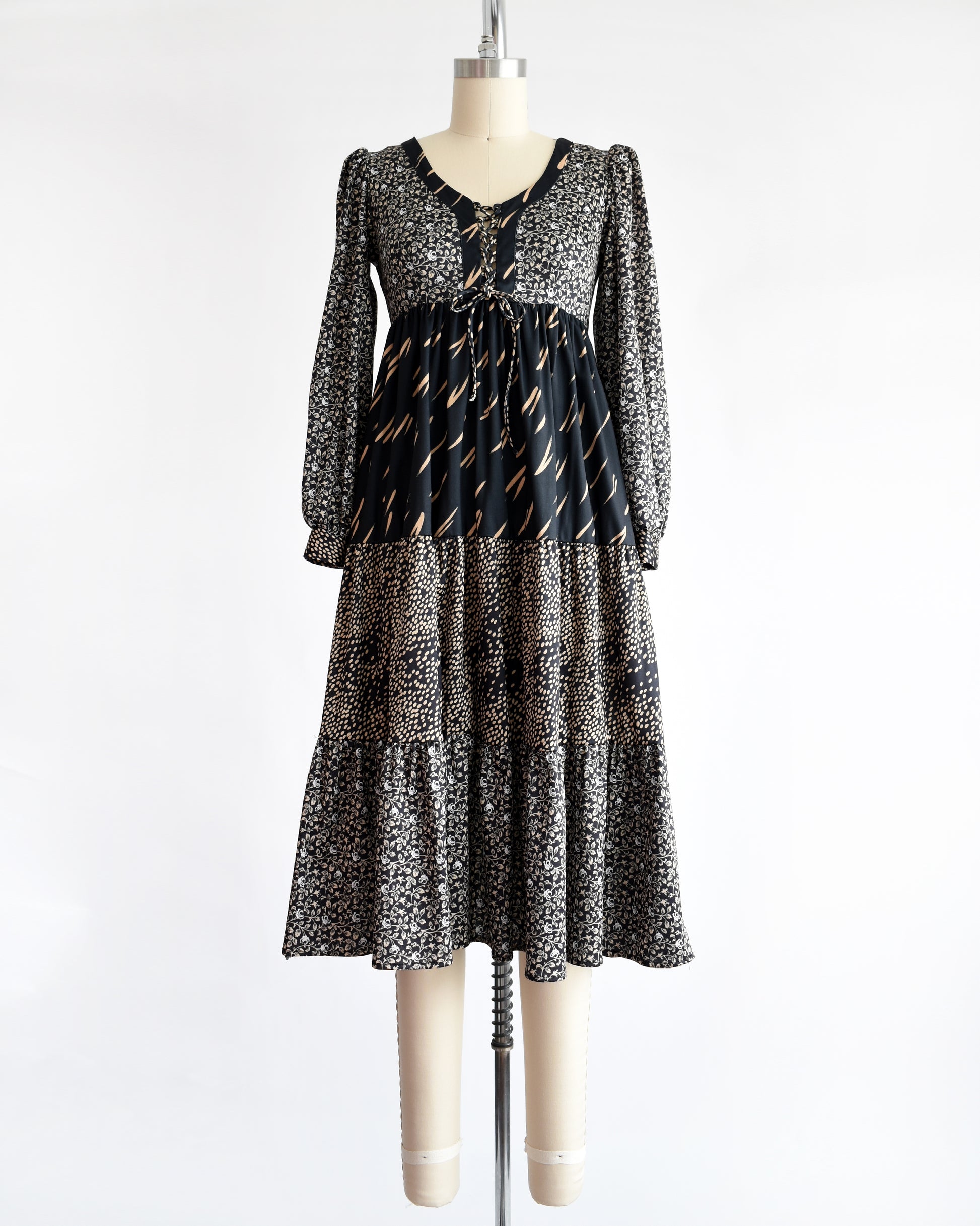 a vintage 1970s black floral dress on a mannequin against a white background
