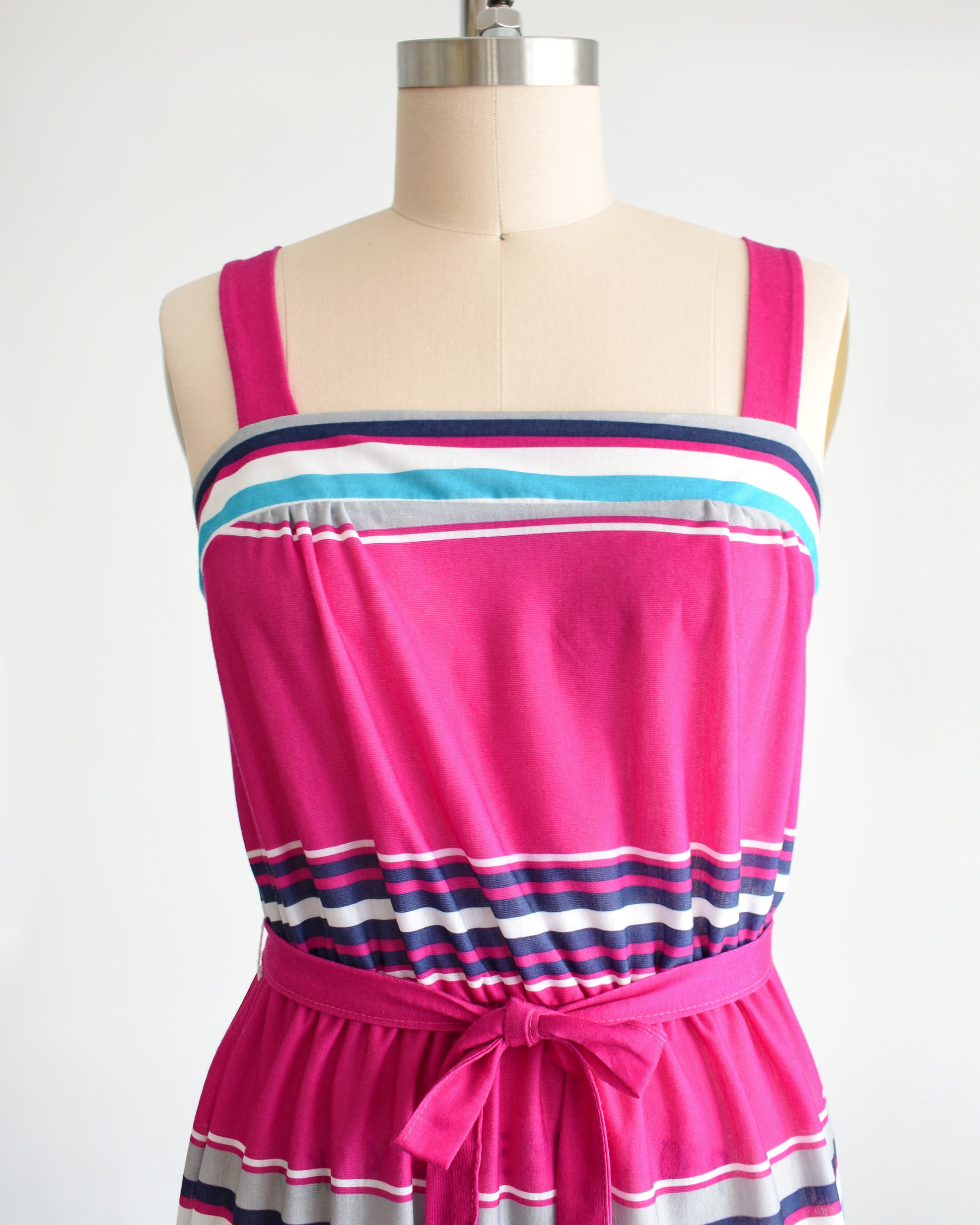close up of the square neckline of a vintage 1970s/1980s sundress that has  horizontal stripes in magenta, light blue, navy blue, gray and white, along with a matching belt.