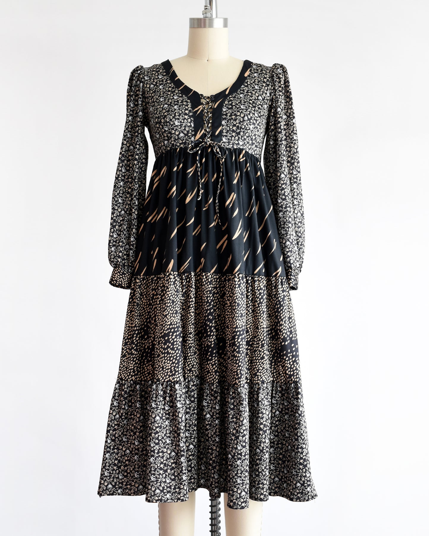 a vintage 1970s black floral dress on a mannequin against a white background