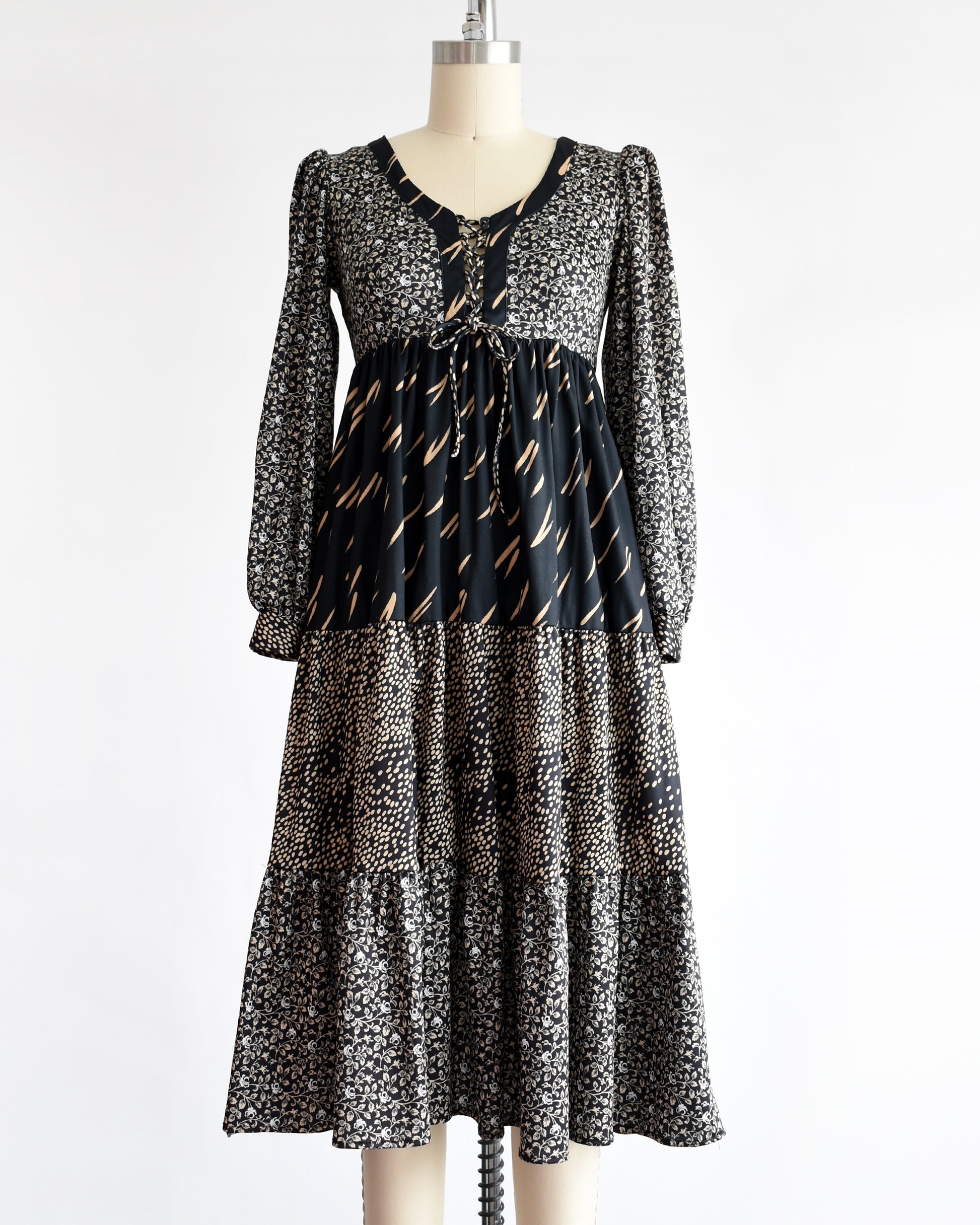 a vintage 1970s black floral dress on a mannequin against a white background